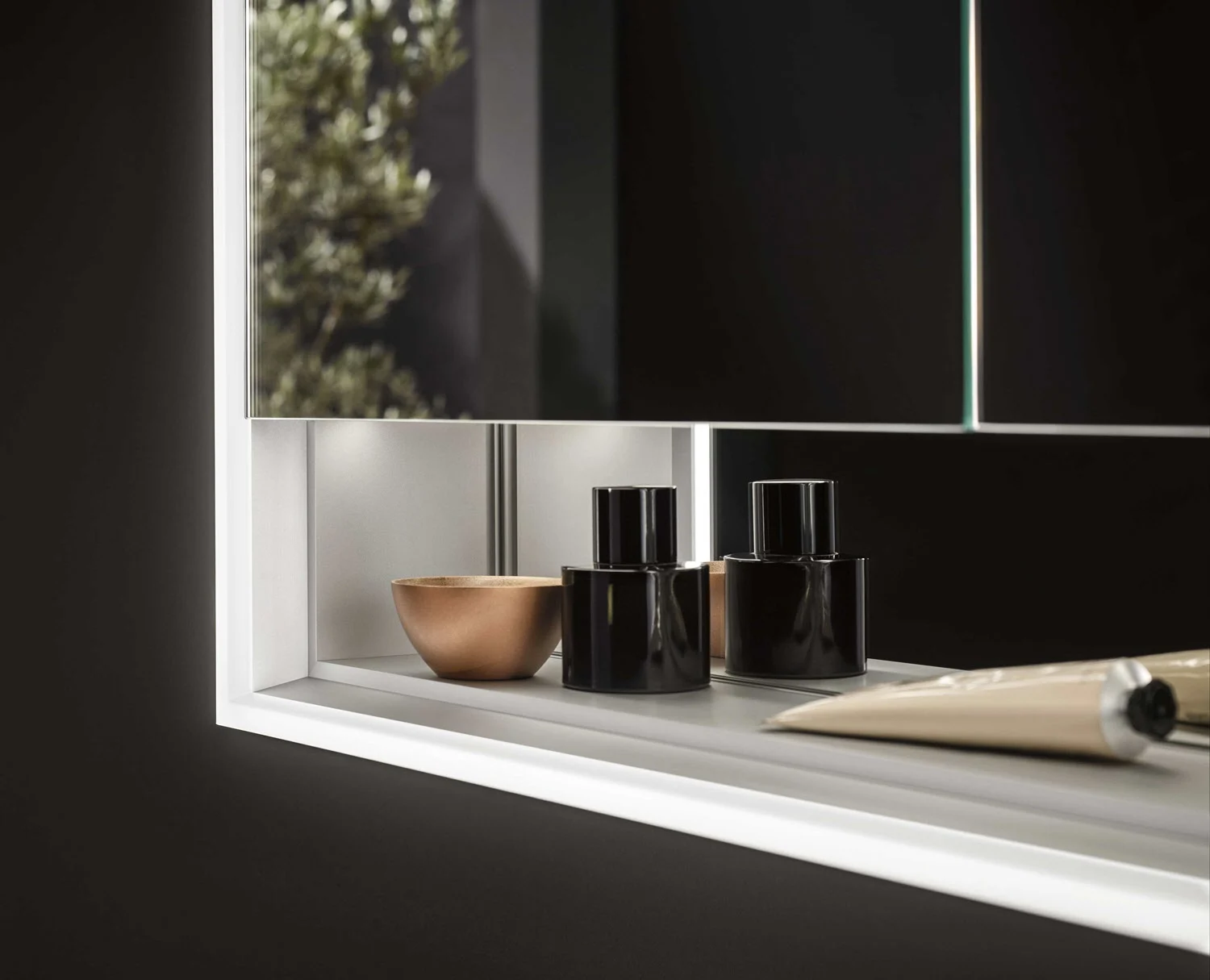 Zbliżenie na podświetlaną szafkę z lustrem i akcesoriami, Emco