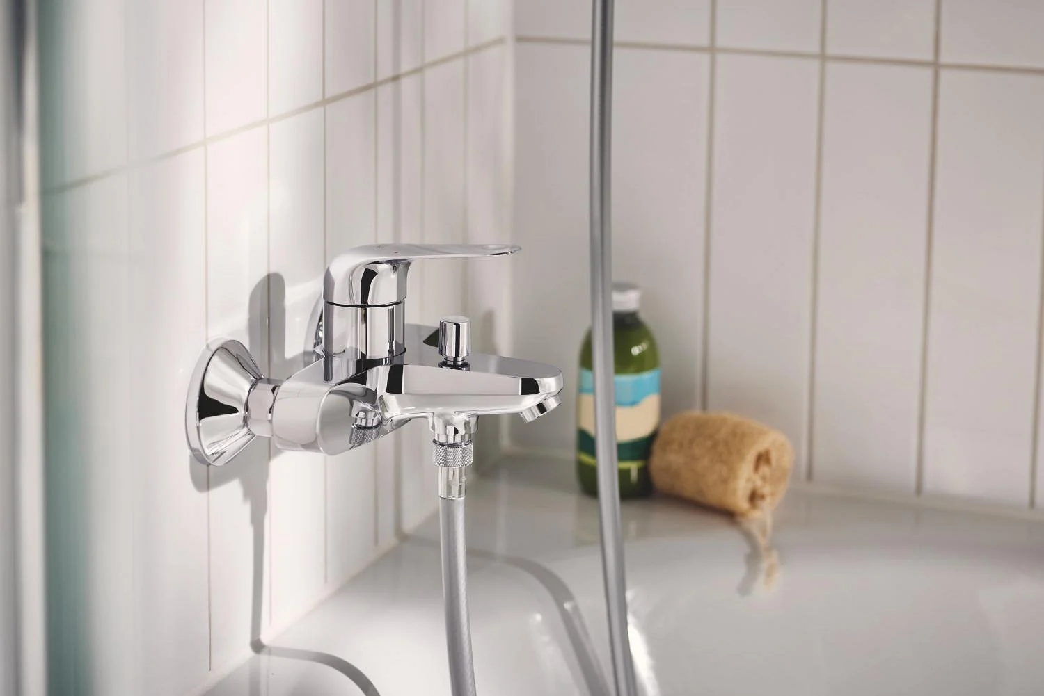Chromowana bateria wannowa na kafelkowanej ścianie łazienki, Grohe