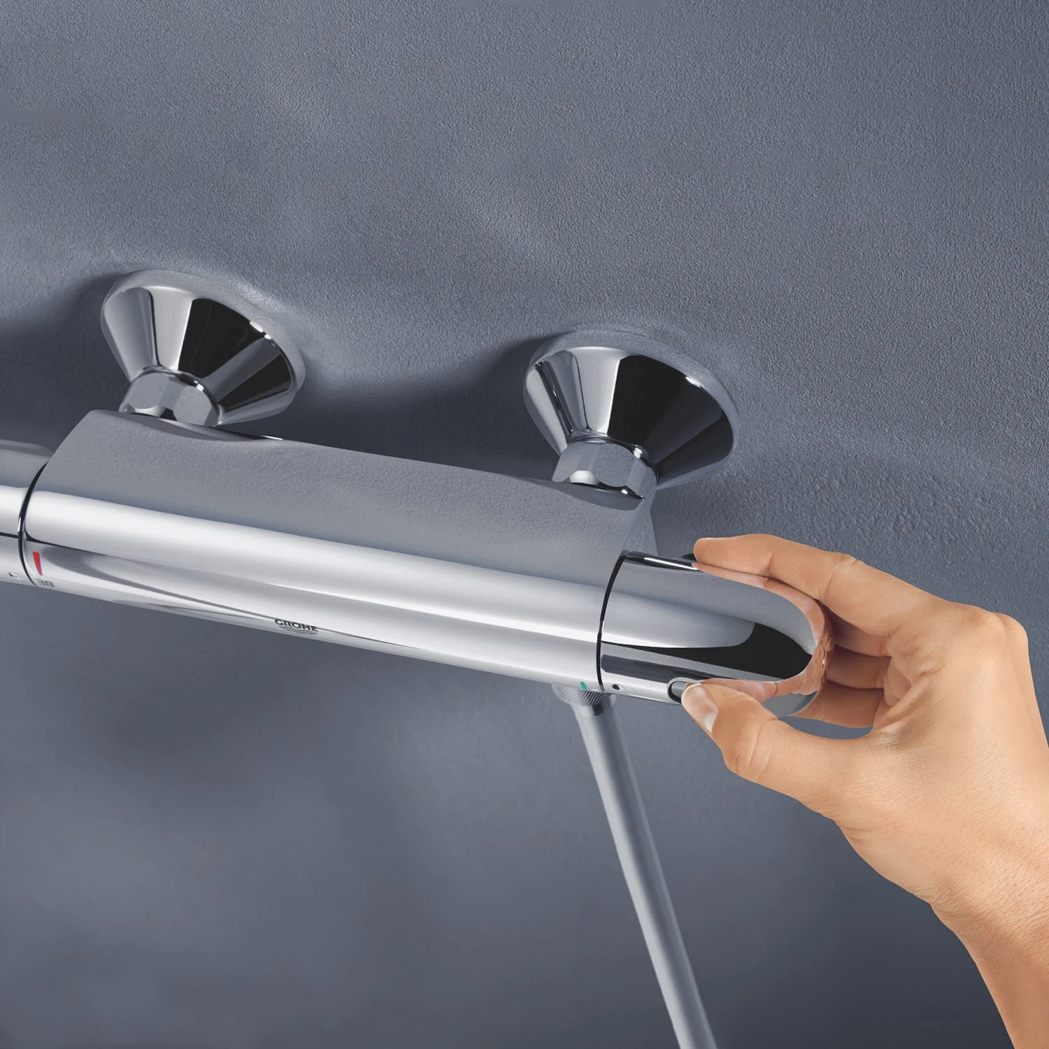 Ręka reguluje chromowaną armaturę termostatyczną, Grohe