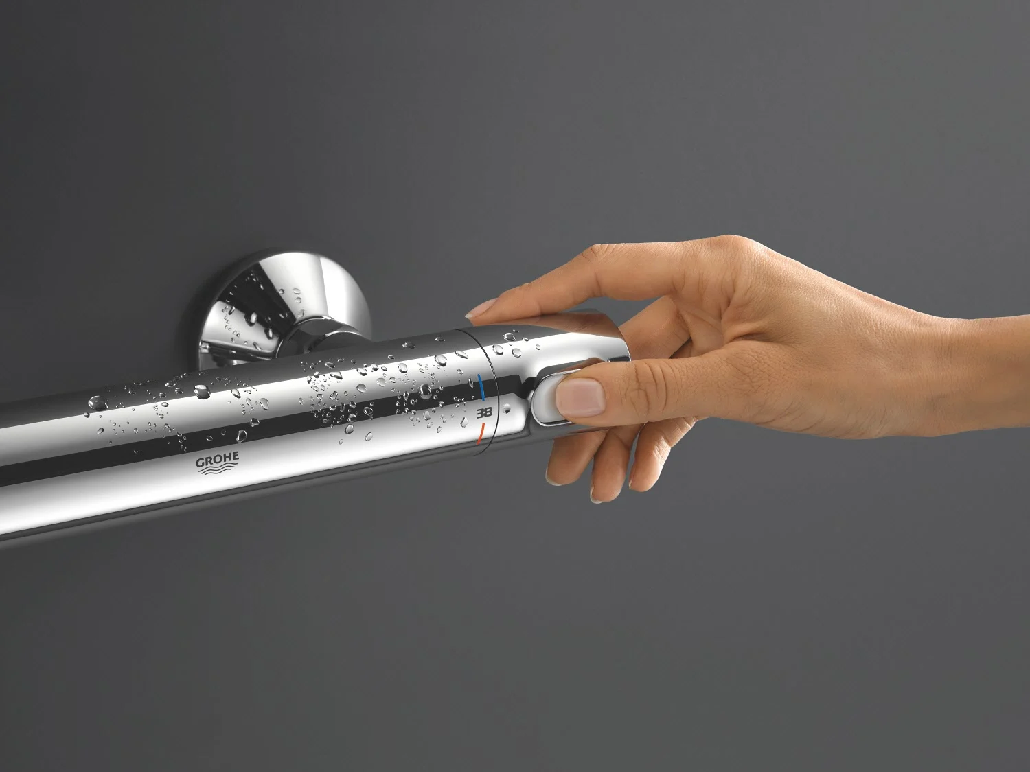 Ręka obsługuje chromowaną armaturę termostatyczną, Grohe