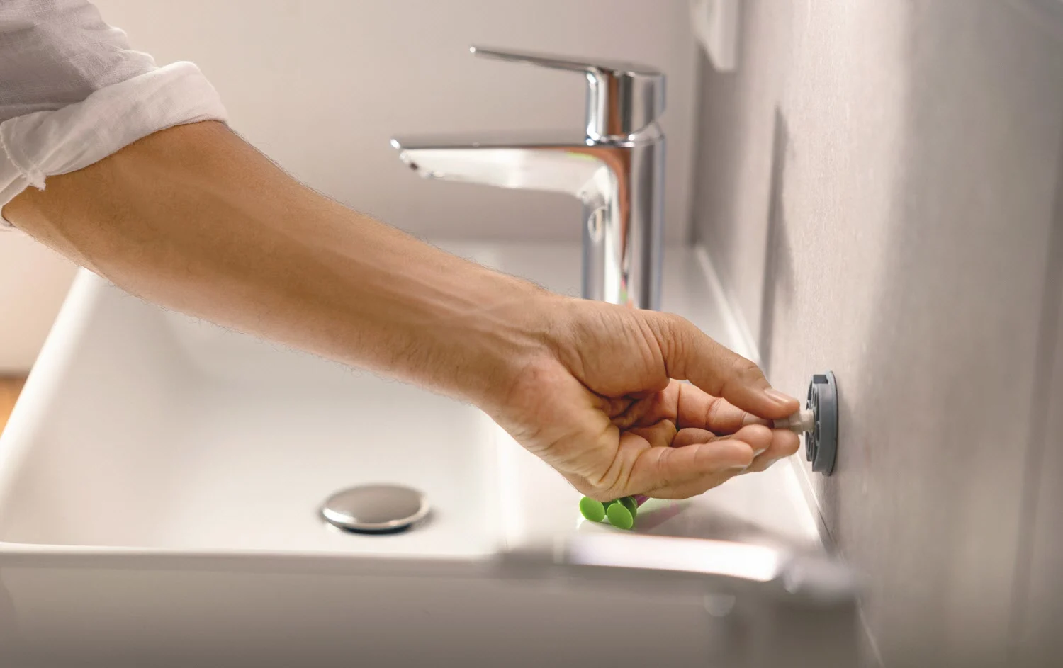 Ręka montuje akcesorium na ścianie umywalki, Grohe
