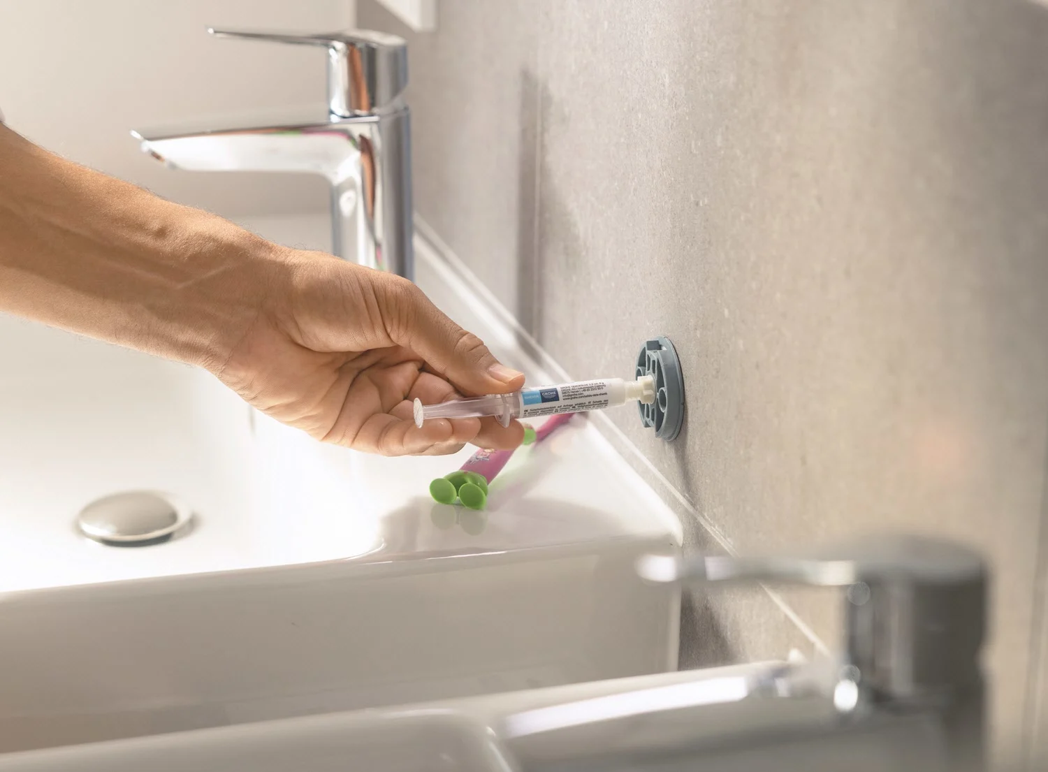 Ręka montuje akcesorium łazienkowe na ścianie, Grohe