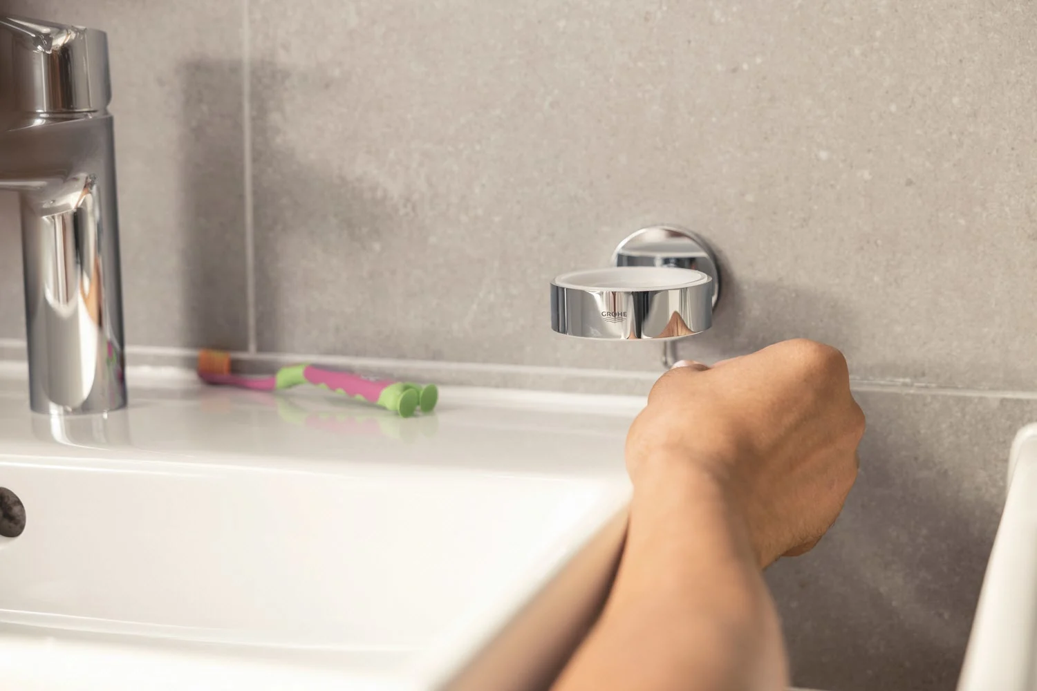 Ręka montuje szklaną półkę w łazience, Grohe