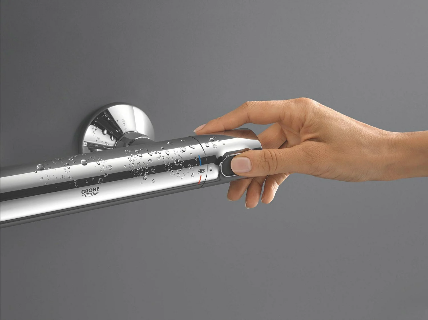 Ręka obsługująca termostat na ścianie, Grohe