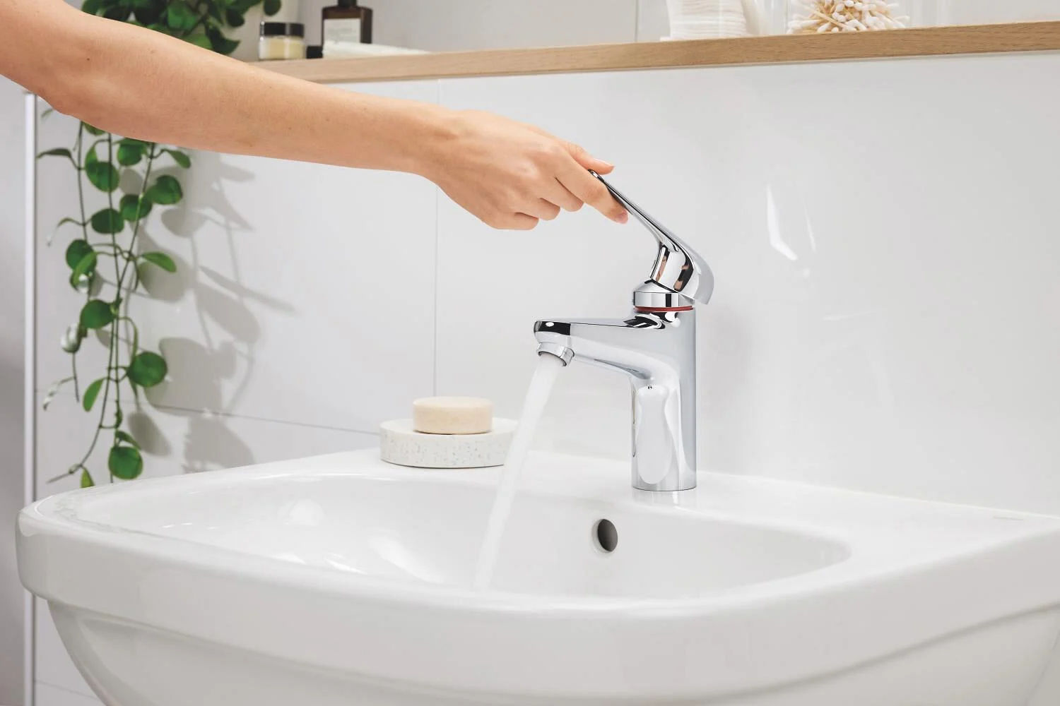 Ręka obsługuje baterię nad umywalką, Grohe