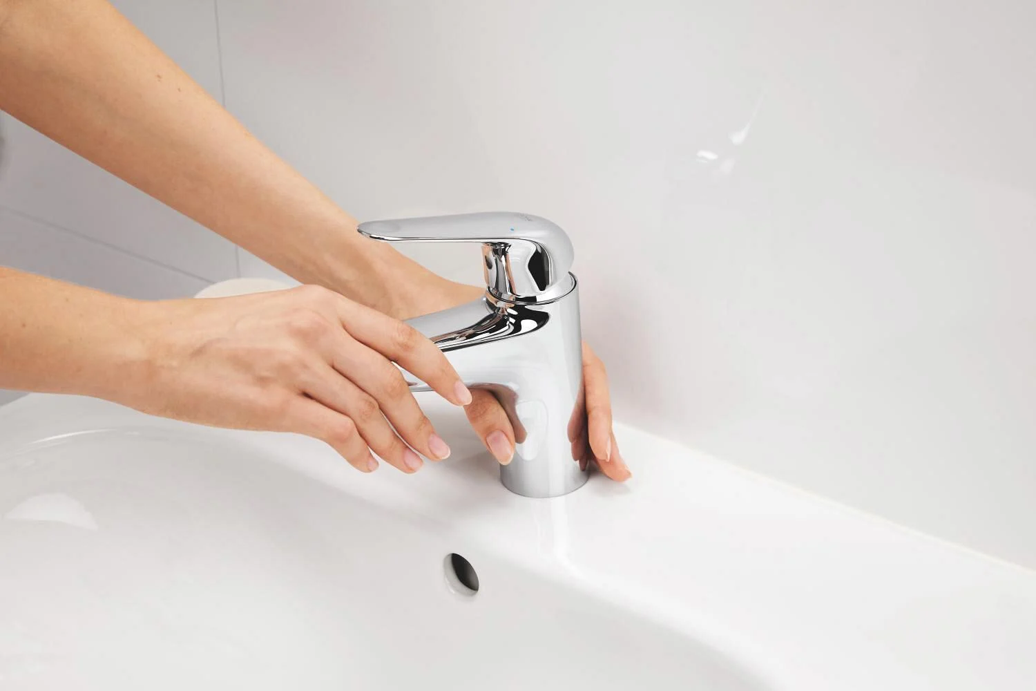 Zbliżenie na chromowaną baterię umywalkową z rękami, Grohe