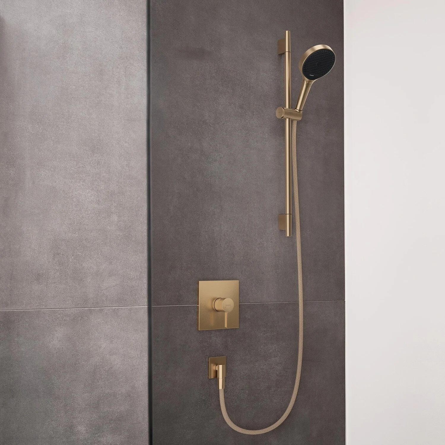 Złota armatura prysznicowa na szarej ścianie, hansgrohe