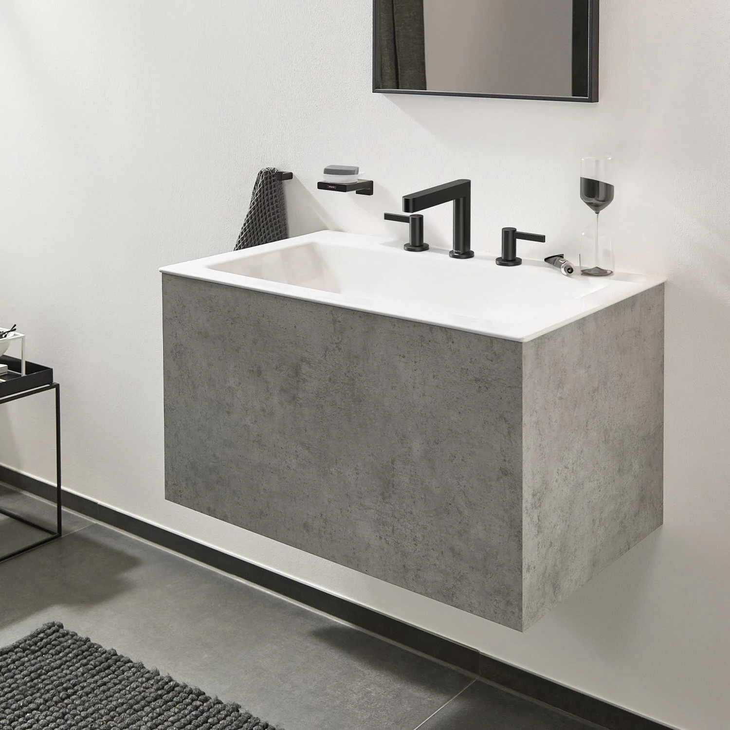 Czarna bateria trójotworowa na szarej umywalce, hansgrohe