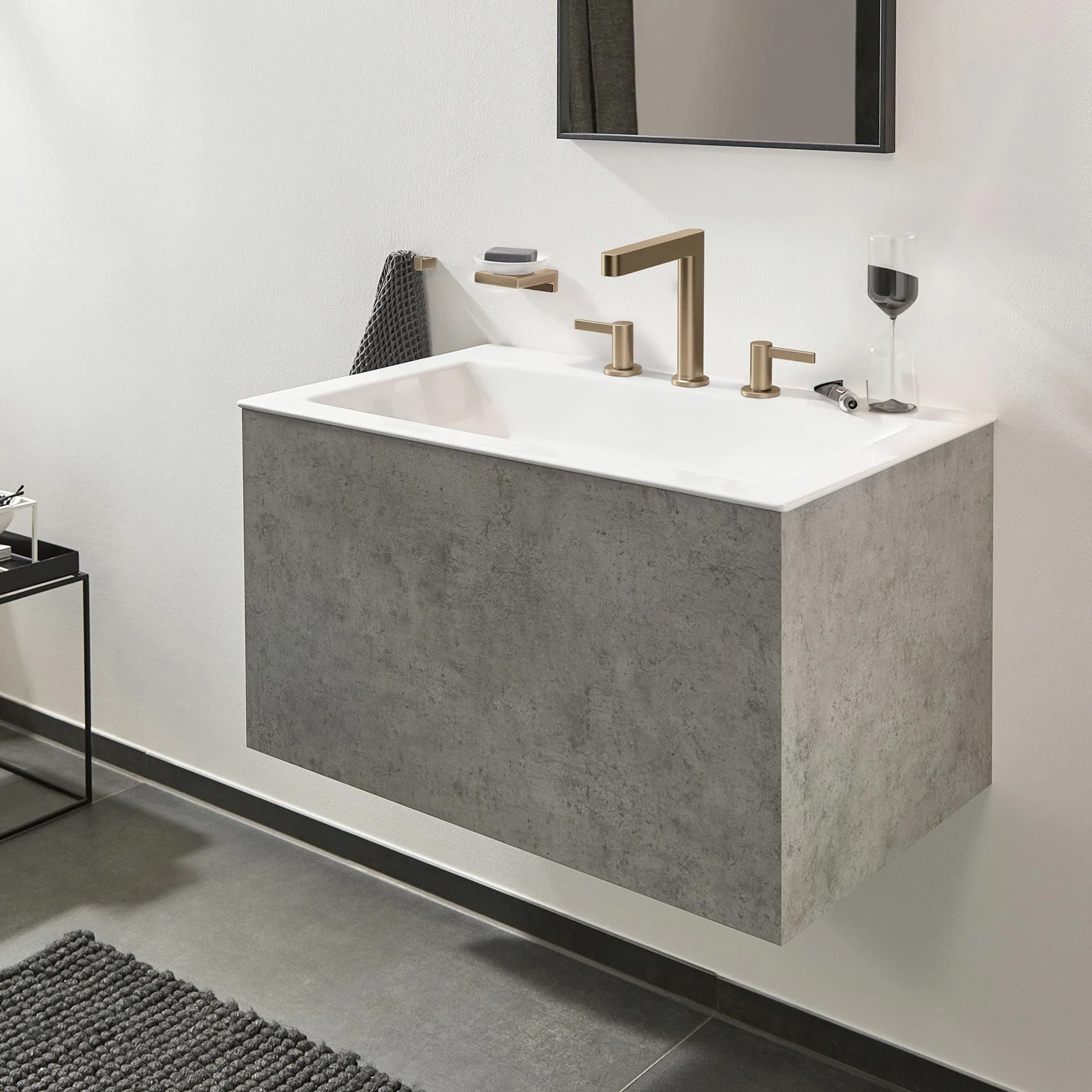 Złota bateria trójotworowa na szarej umywalce, hansgrohe