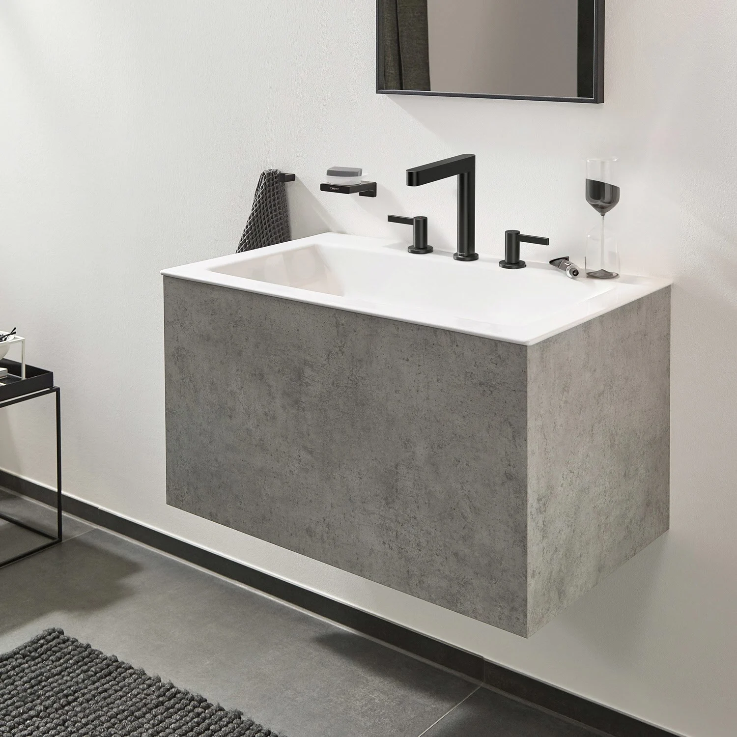 Czarna bateria trójotworowa na szarej umywalce, hansgrohe