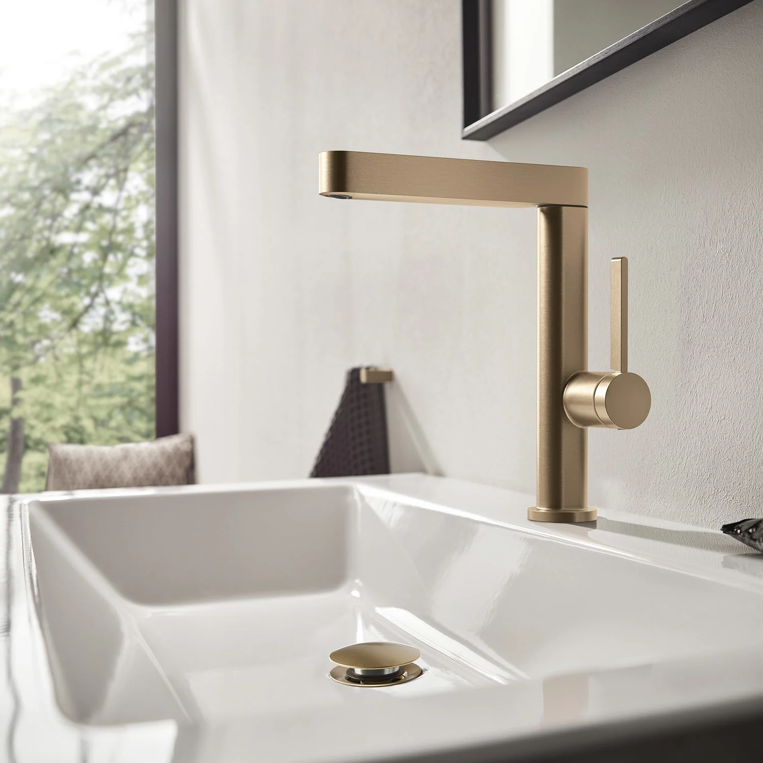 Złoty jednouchwytowy mieszacz przy białej umywalce, hansgrohe