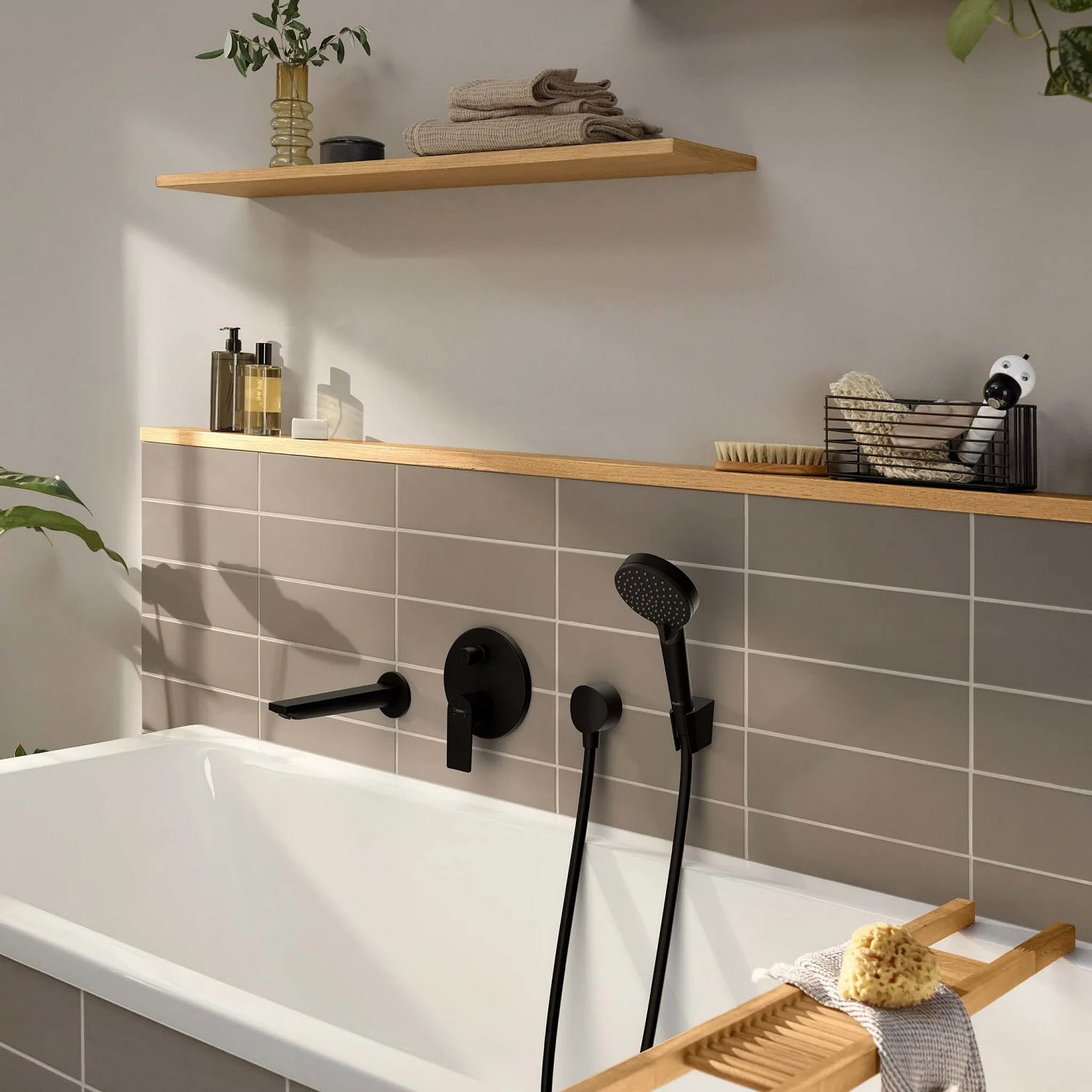 Czarna bateria łazienkowa na kafelkowanej wannie, hansgrohe