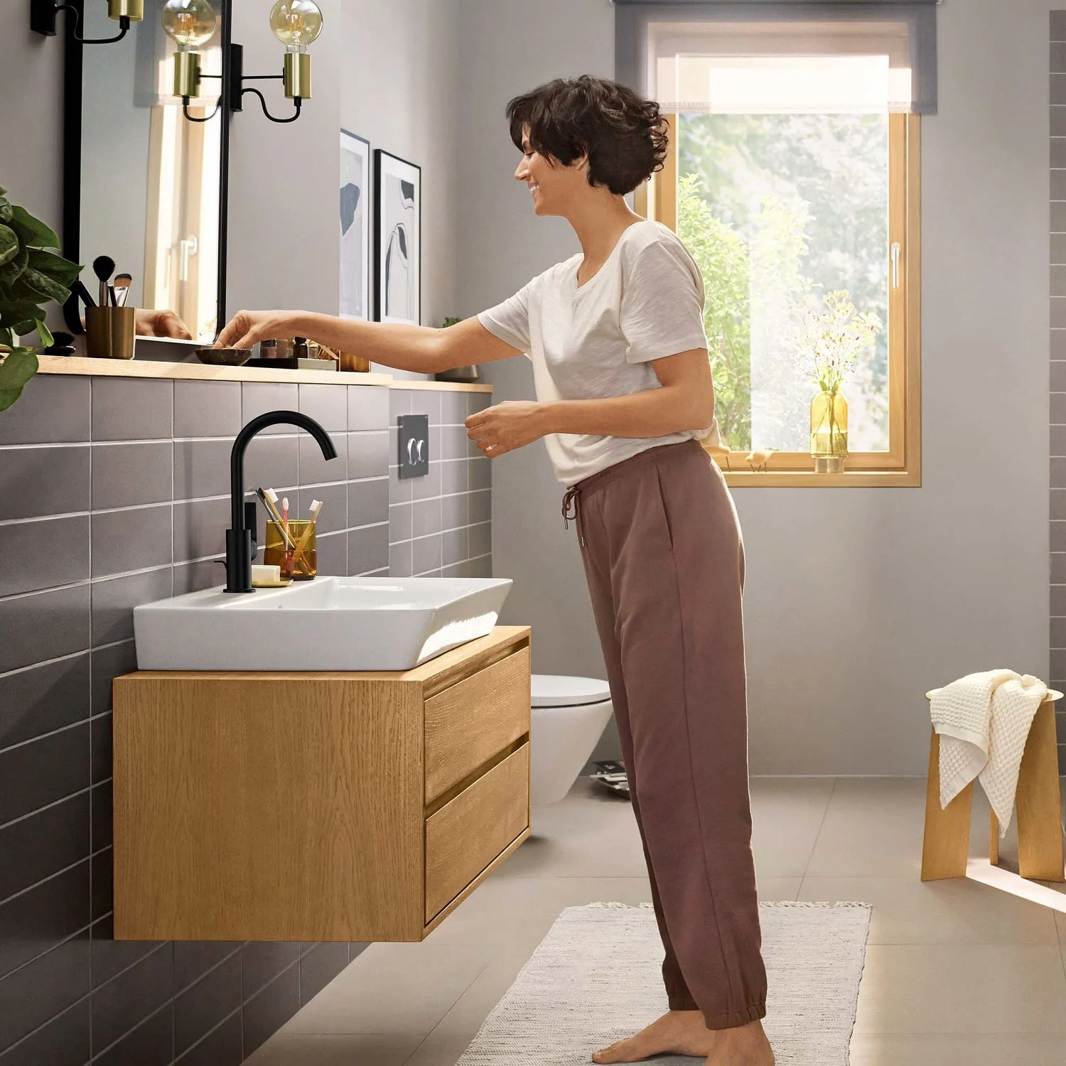 Kobieta w łazience z czarną baterią umywalkową, hansgrohe