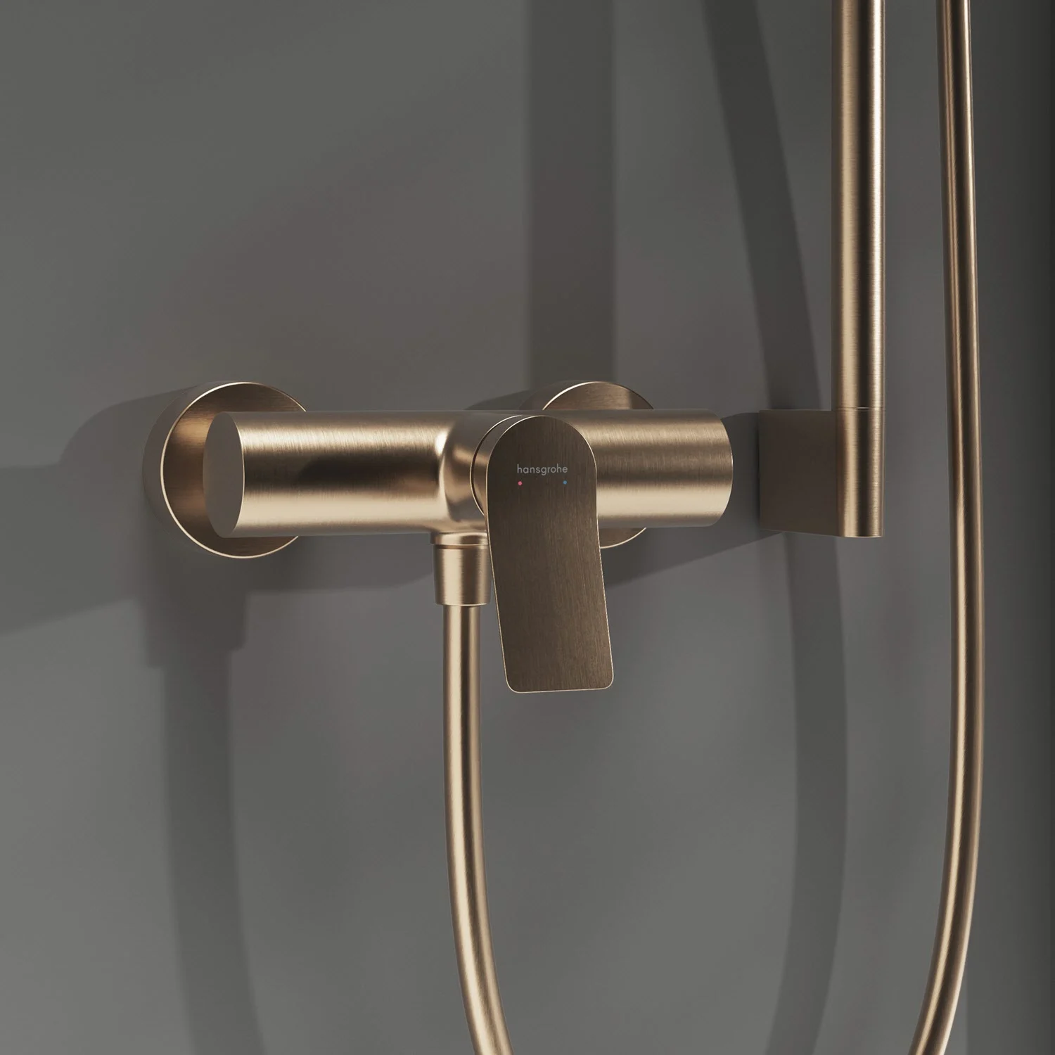 Złota armatura prysznicowa zamontowana na szarej ścianie, hansgrohe