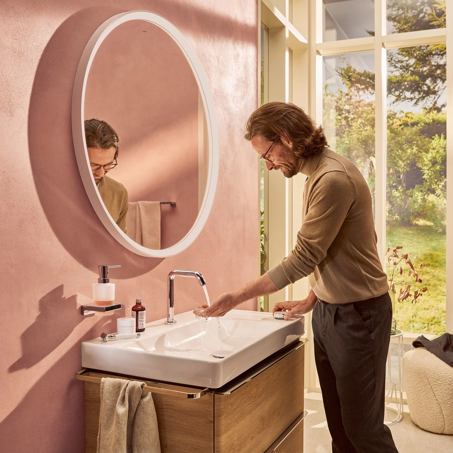 Mężczyzna myjący ręce przy umywalce w łazience, hansgrohe
