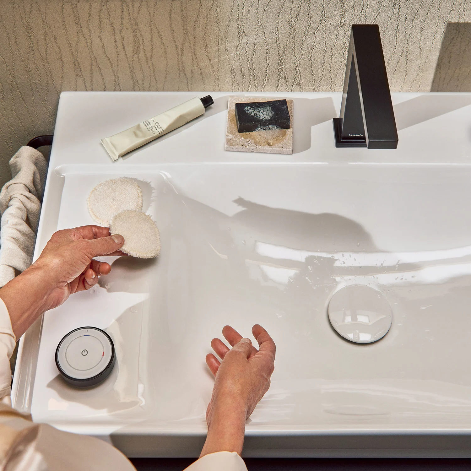 Osoba używająca umywalki z produktami pielęgnacyjnymi, hansgrohe
