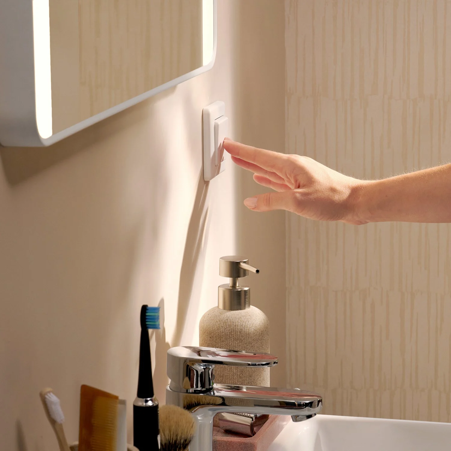 Ręka obsługuje włącznik światła obok umywalki, hansgrohe