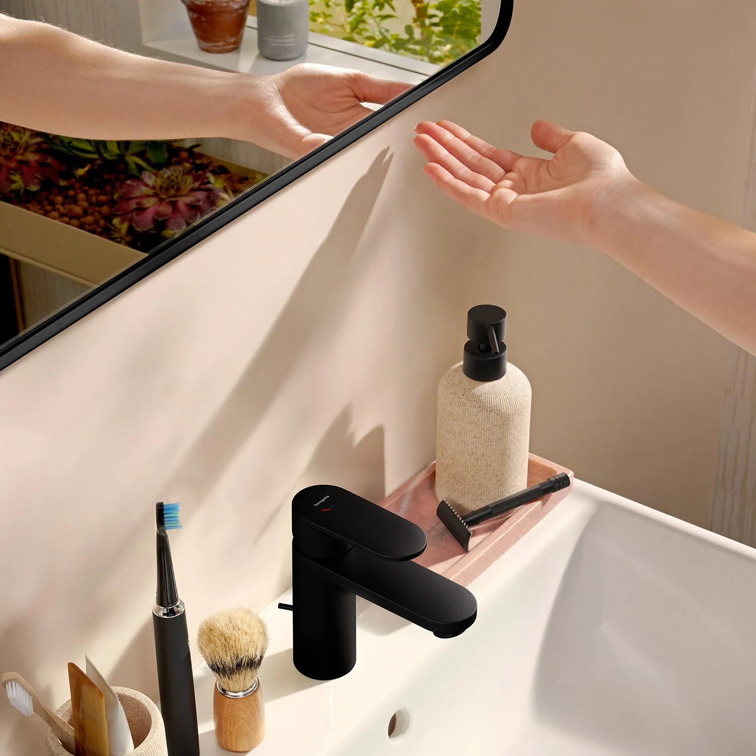 Zbliżenie kranu z ręką w łazience, hansgrohe