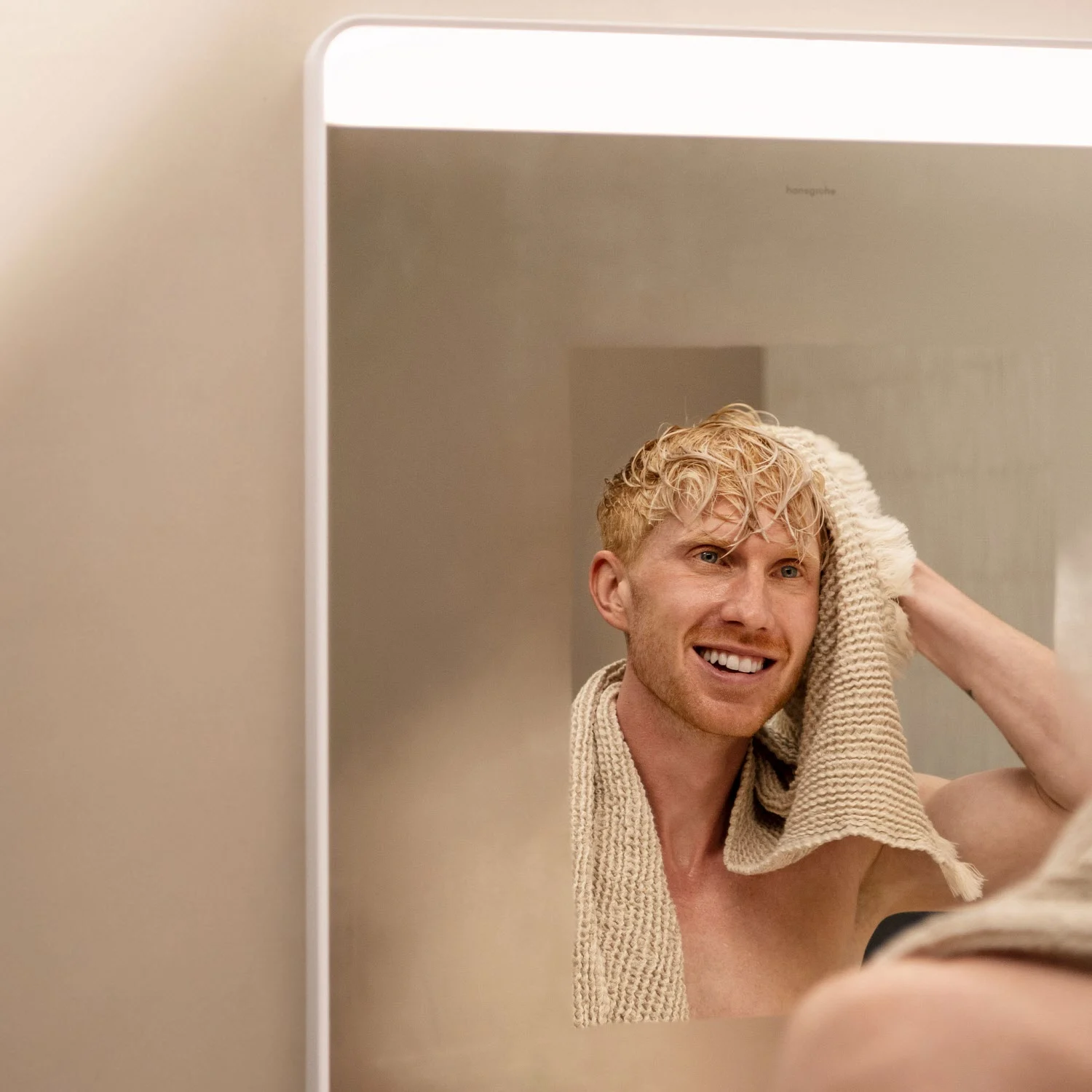 Mężczyzna suszy się przed prostokątnym lustrem, hansgrohe