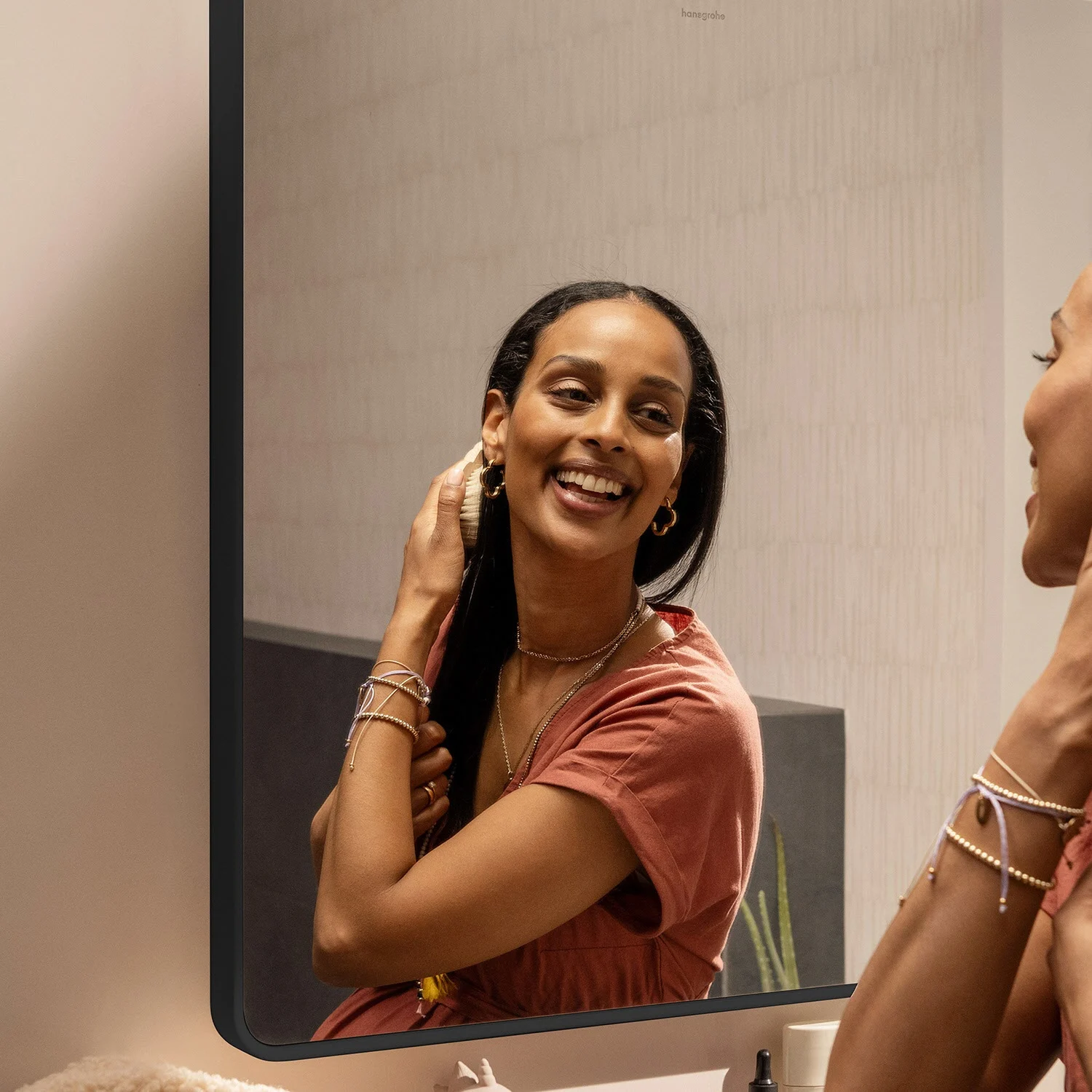 Kobieta patrzy na siebie w prostokątnym lustrze, hansgrohe