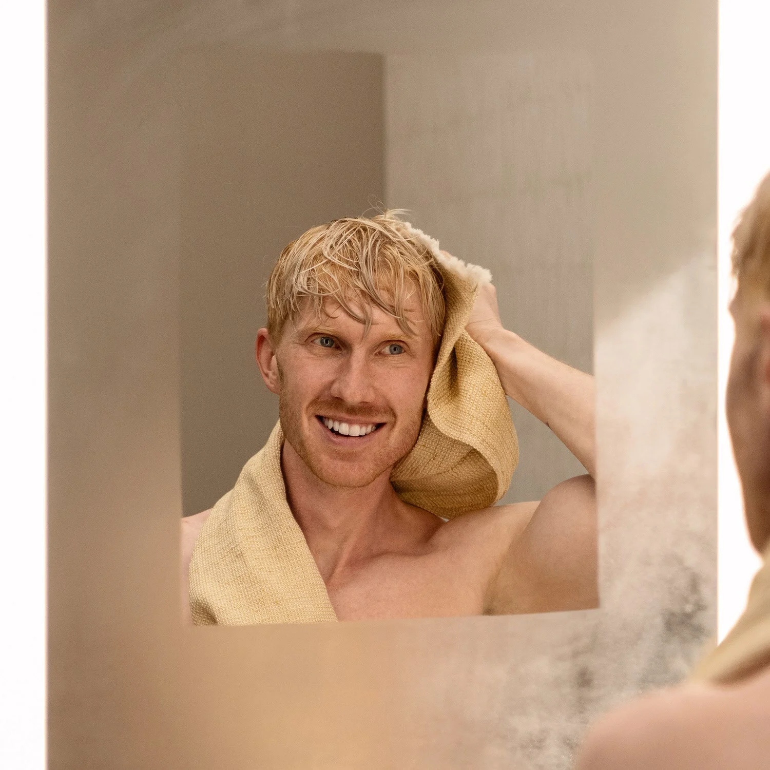 Mężczyzna suszy się przed prostokątnym lustrem, hansgrohe