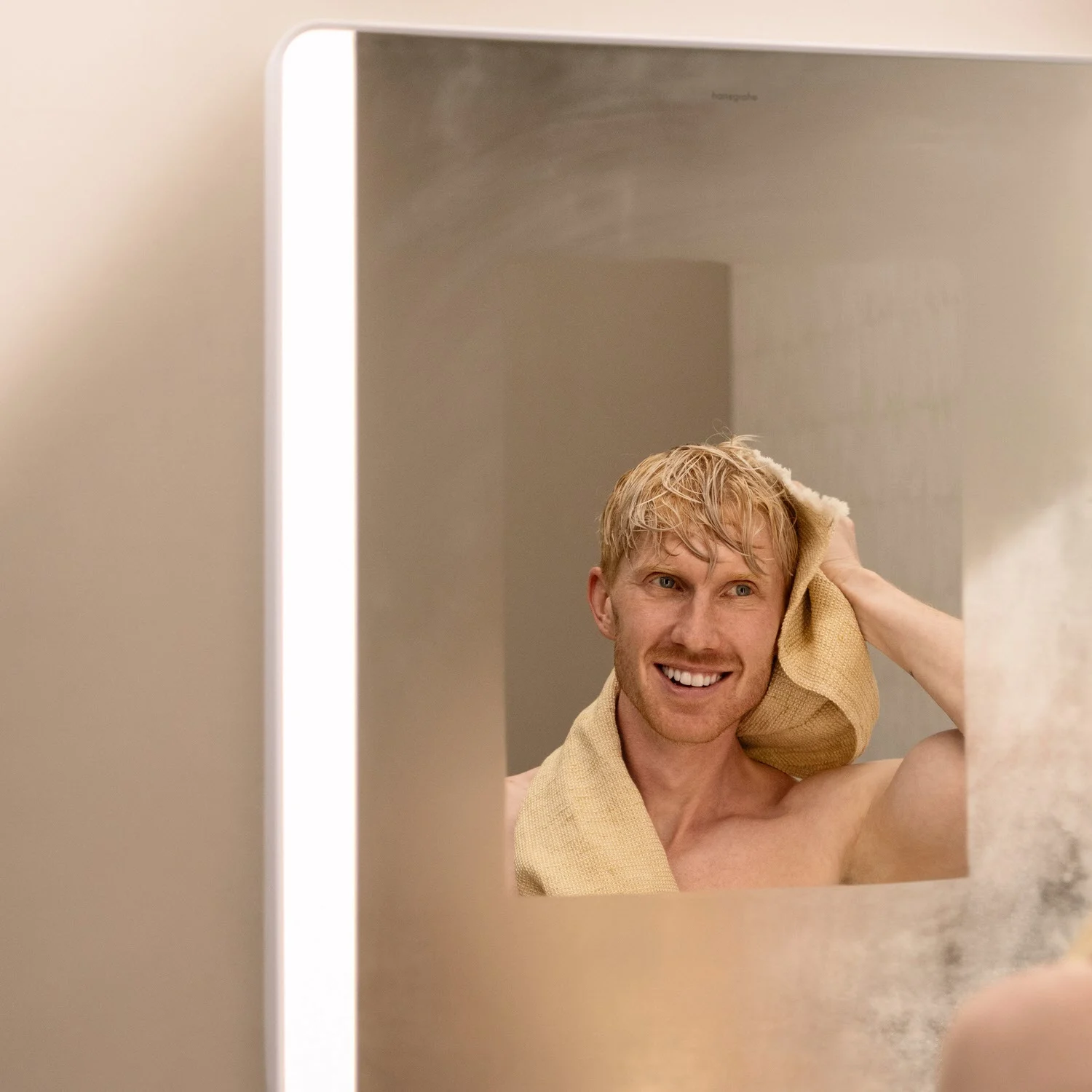 Mężczyzna suszy się przed prostokątnym lustrem, hansgrohe