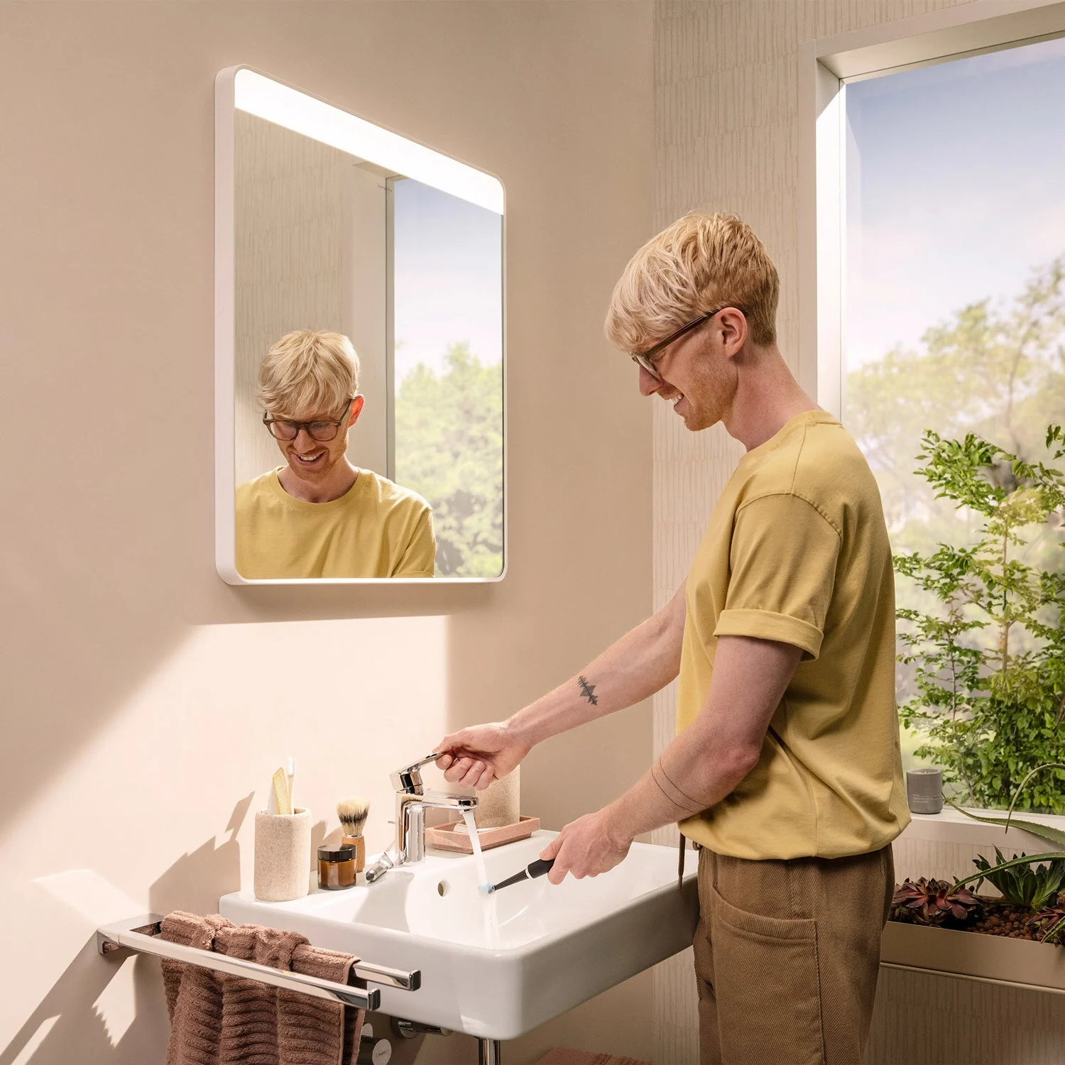 Osoba myjąca ręce przy umywalce z lustrem, hansgrohe