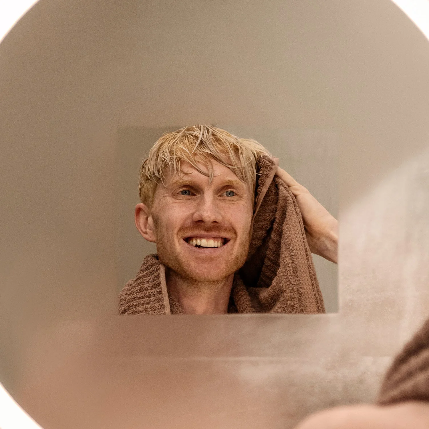 Mężczyzna suszy się przed podświetlanym lustrem, hansgrohe