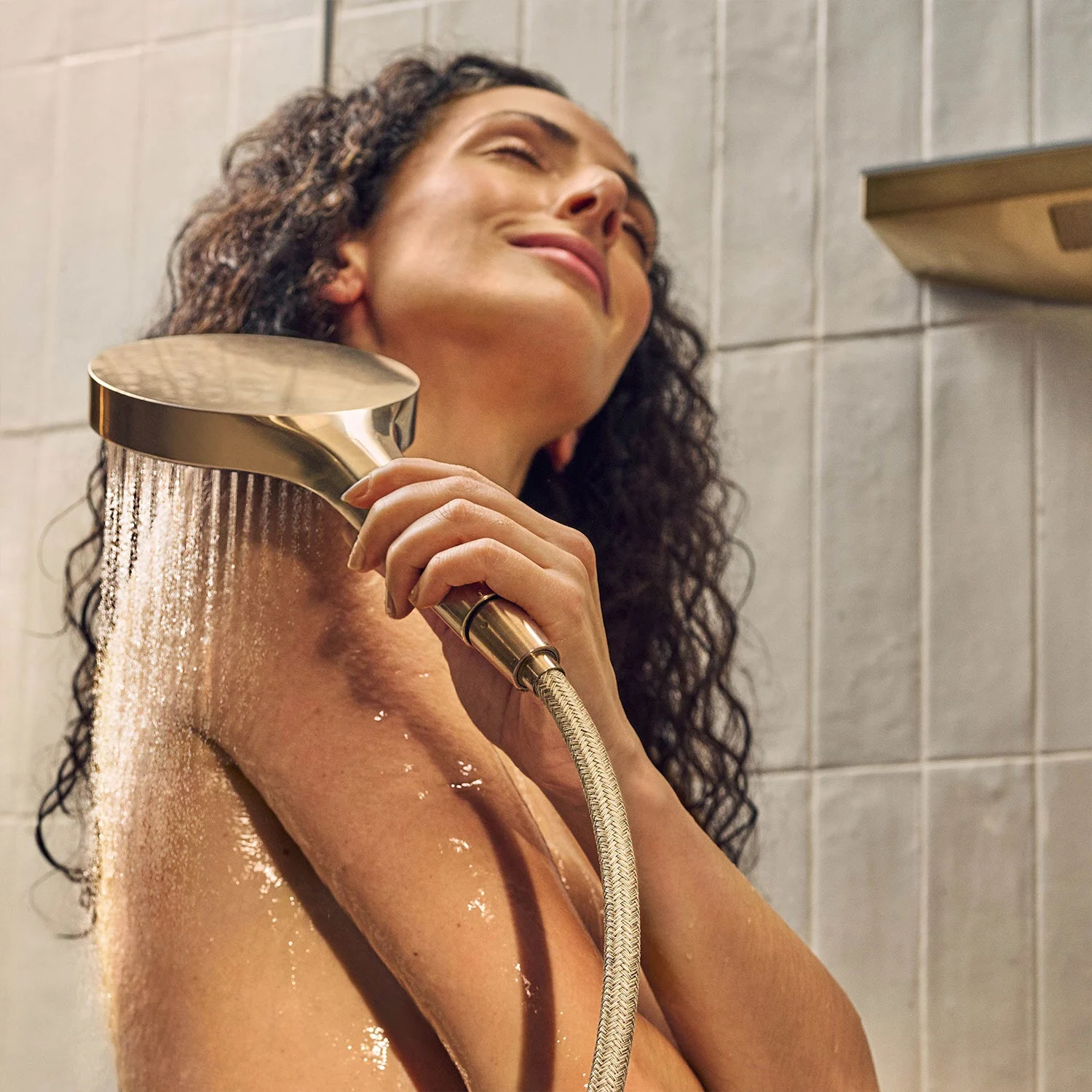 Osoba bierze prysznic z rączką prysznicową w łazience, hansgrohe