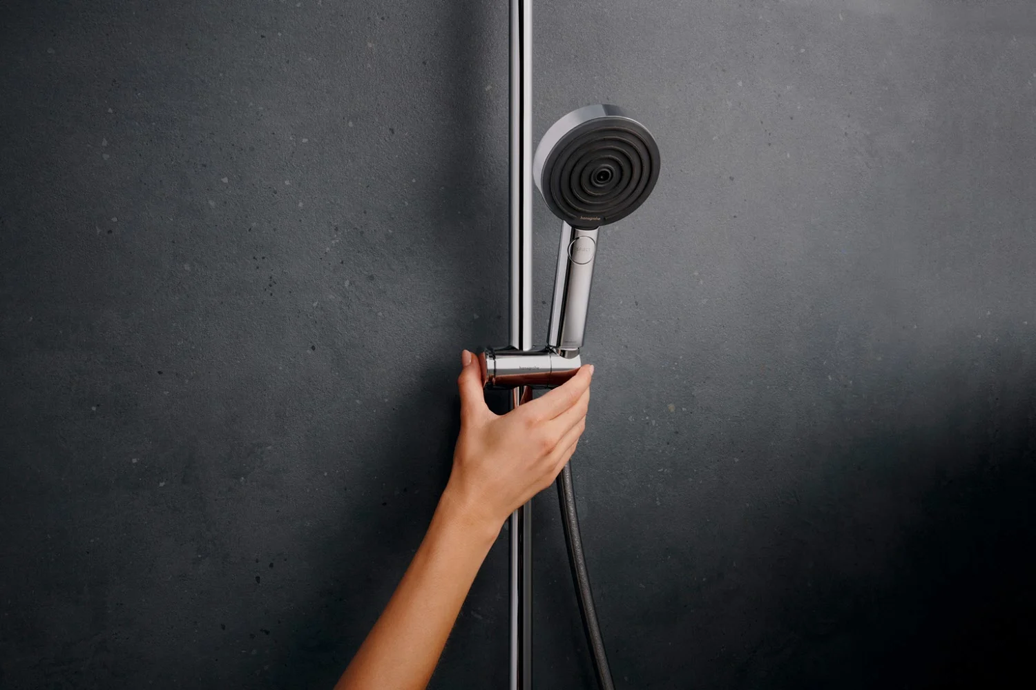 Ręka reguluje głowicę prysznicową na ścianie, hansgrohe
