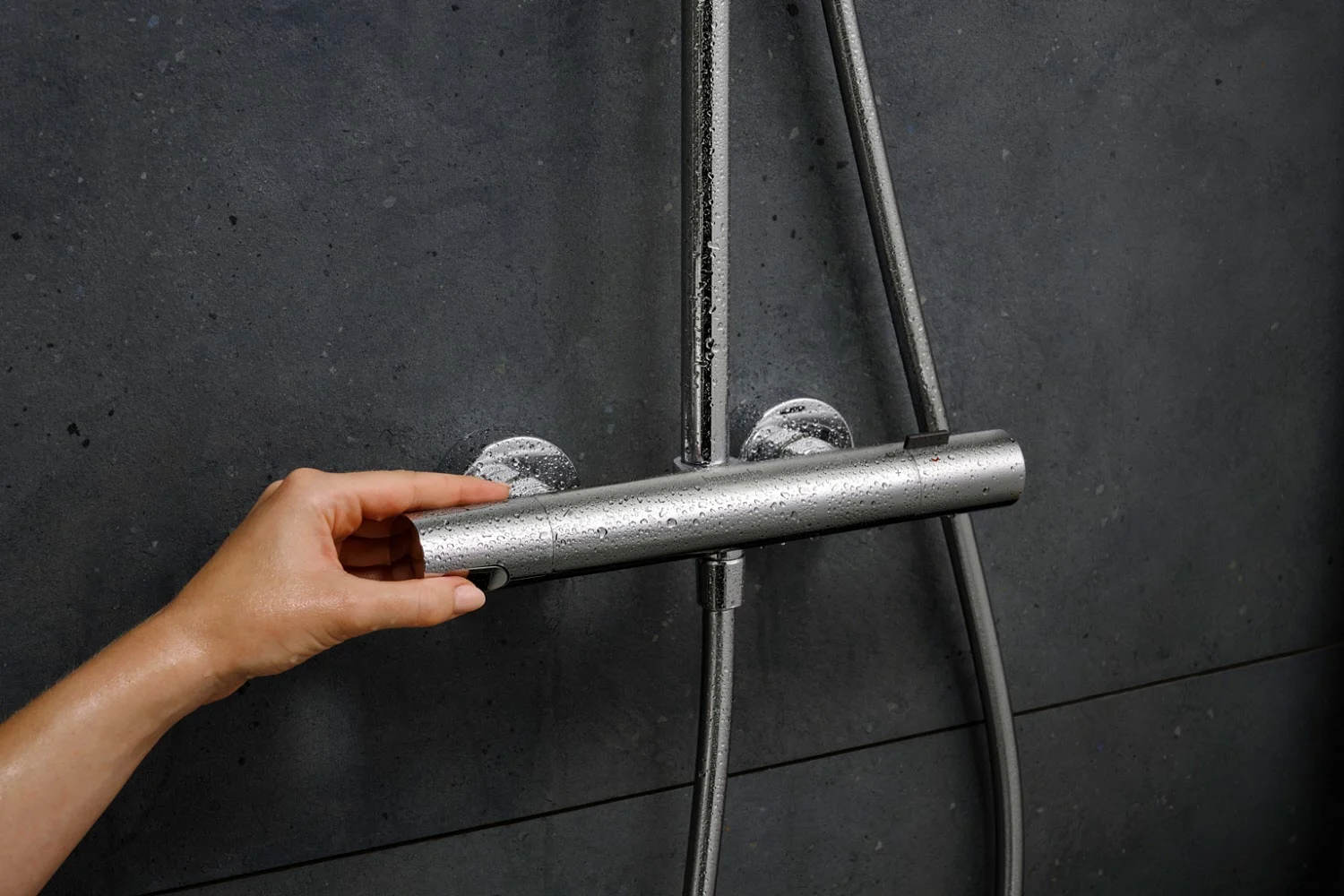 Ręka obraca srebrny termostat prysznicowy, hansgrohe