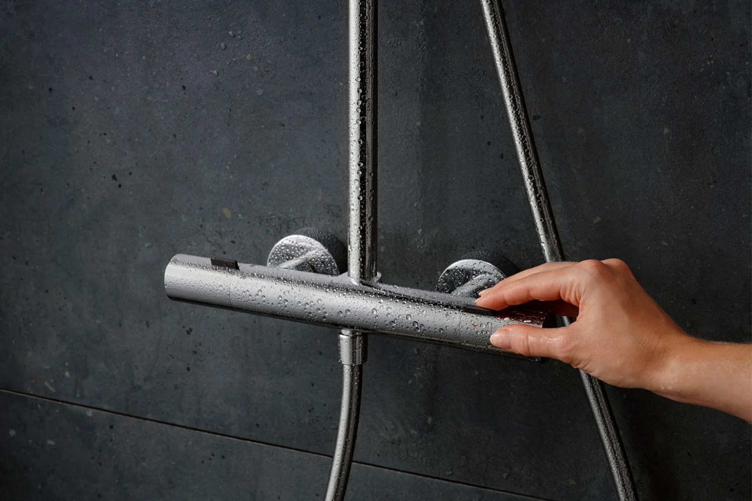 Ręka reguluje armaturę prysznicową na ścianie, hansgrohe