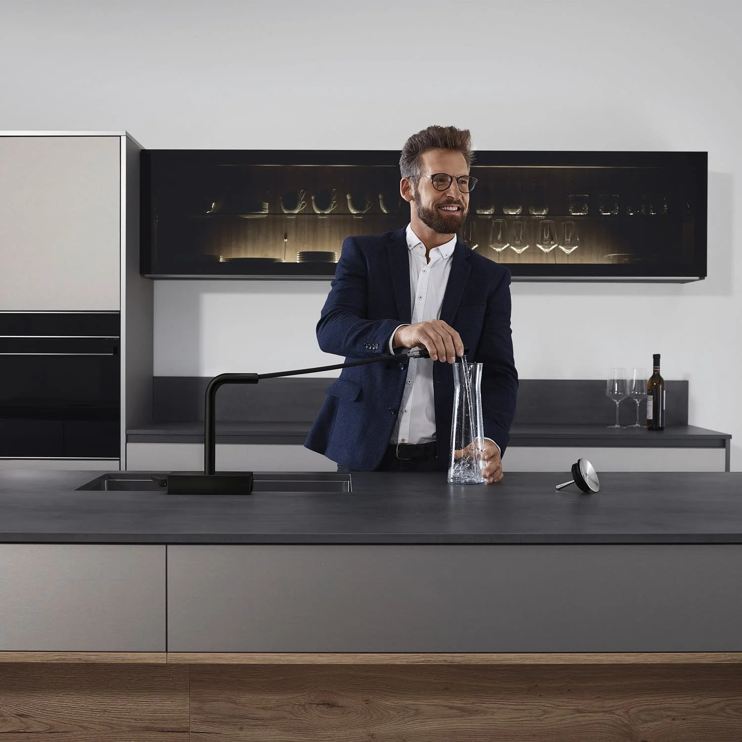 Mężczyzna używa czarnej baterii kuchennej w nowoczesnej kuchni, hansgrohe