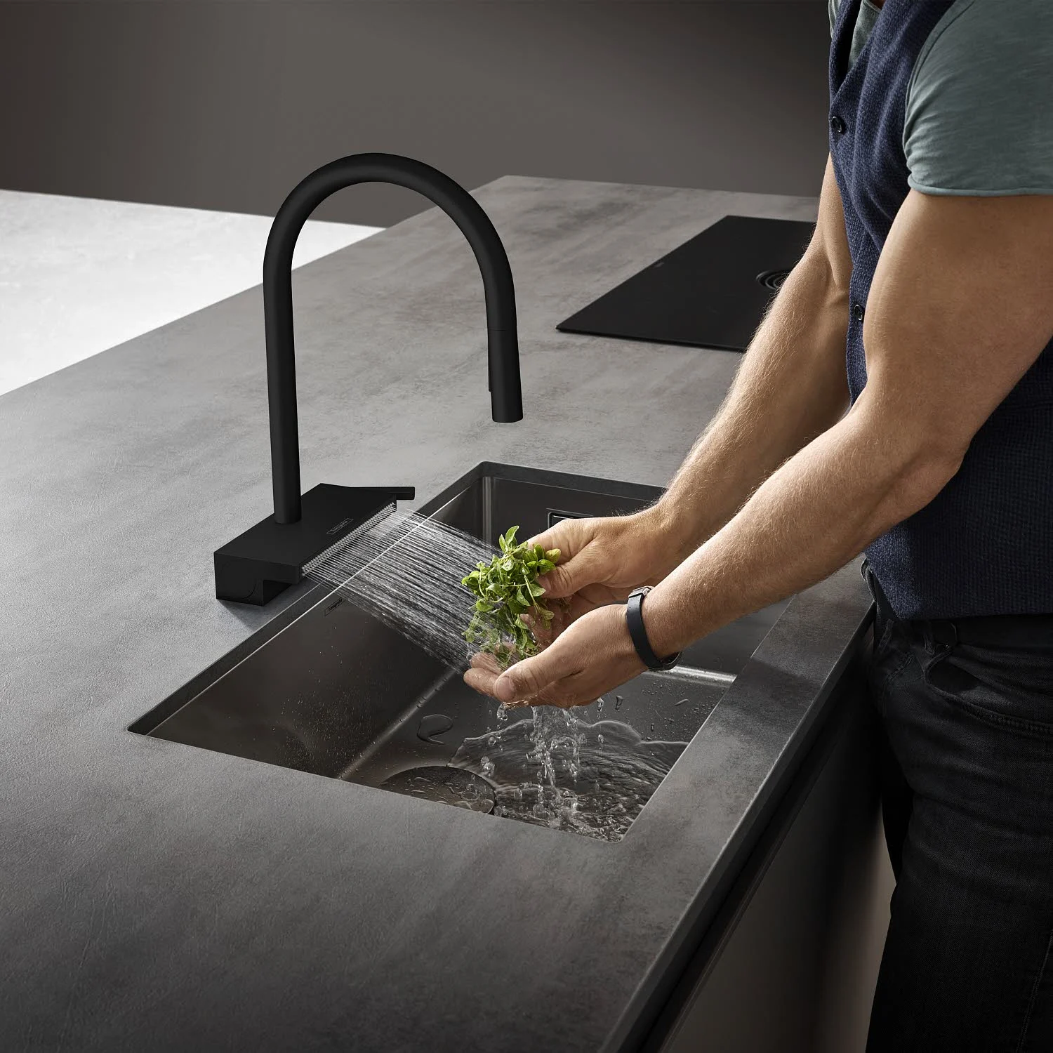Mężczyzna myje warzywa pod czarną baterią kuchenną, hansgrohe