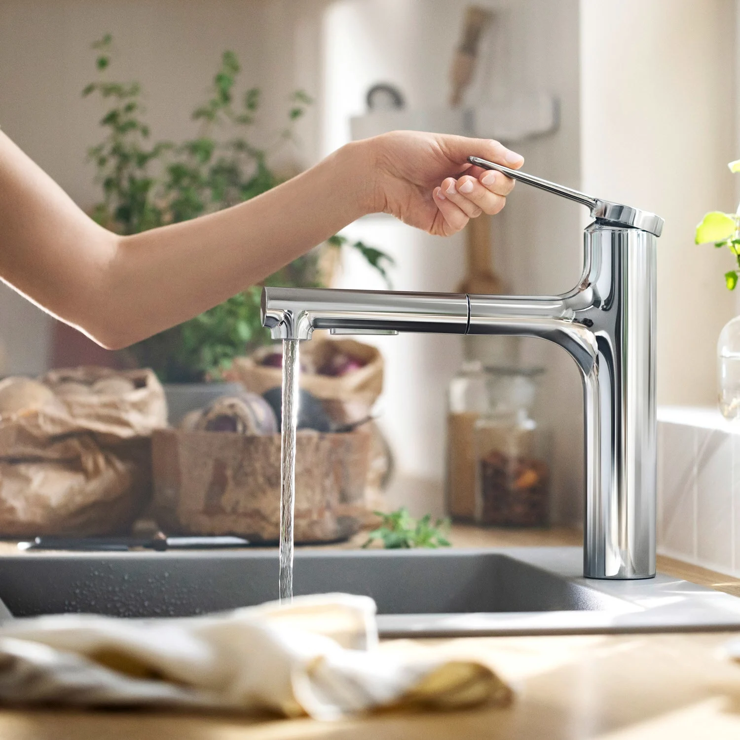 Ręka obsługująca baterię kuchenną w nowoczesnej kuchni, hansgrohe