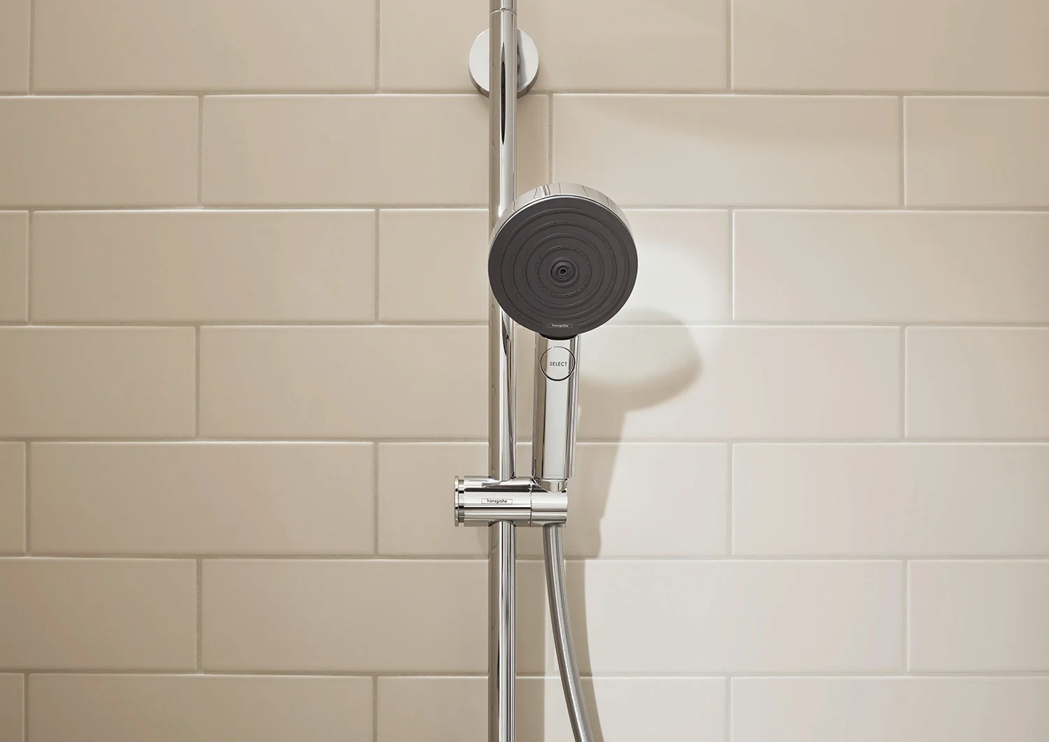 Głowica prysznicowa i szyna na tle ściany z płytek, hansgrohe