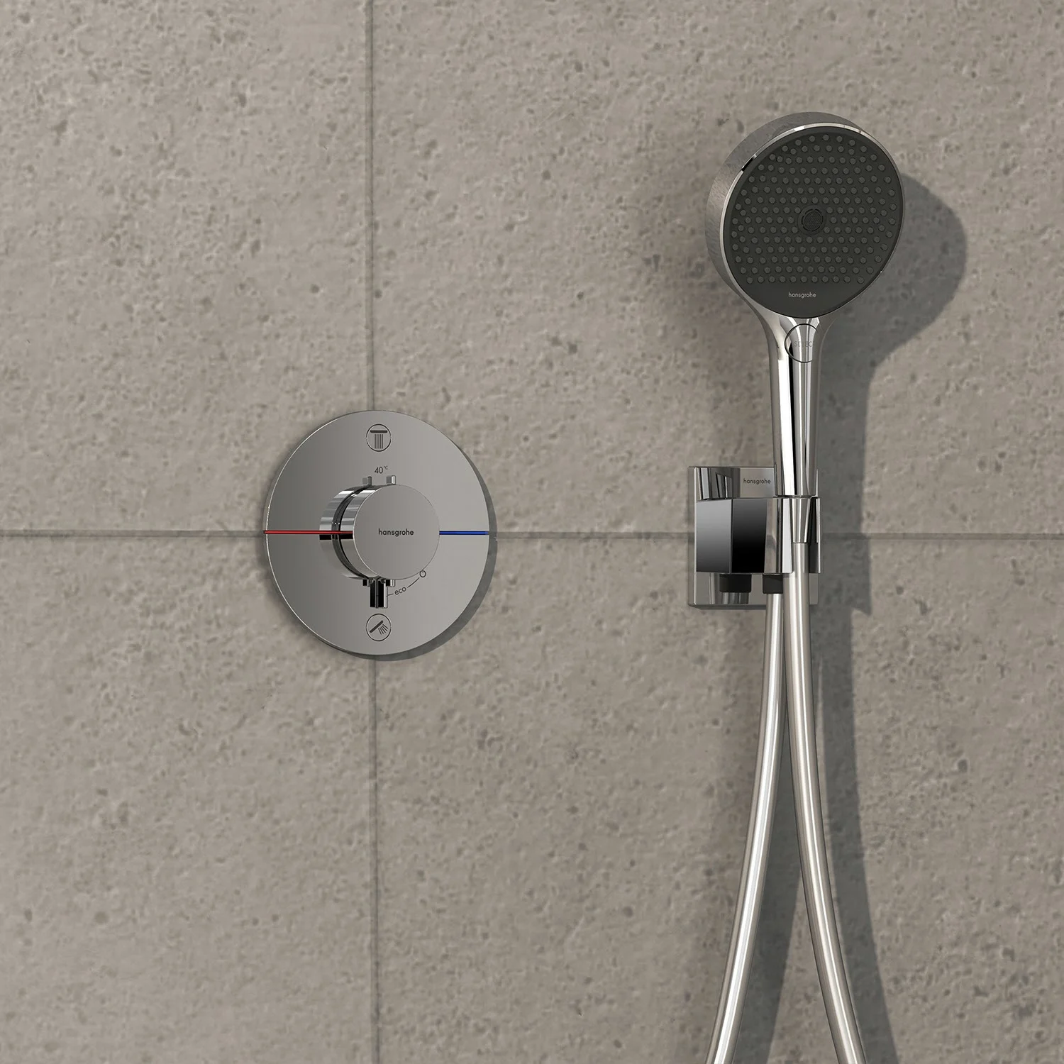 Chromowana armatura prysznicowa na szarej ścianie z płytek, hansgrohe