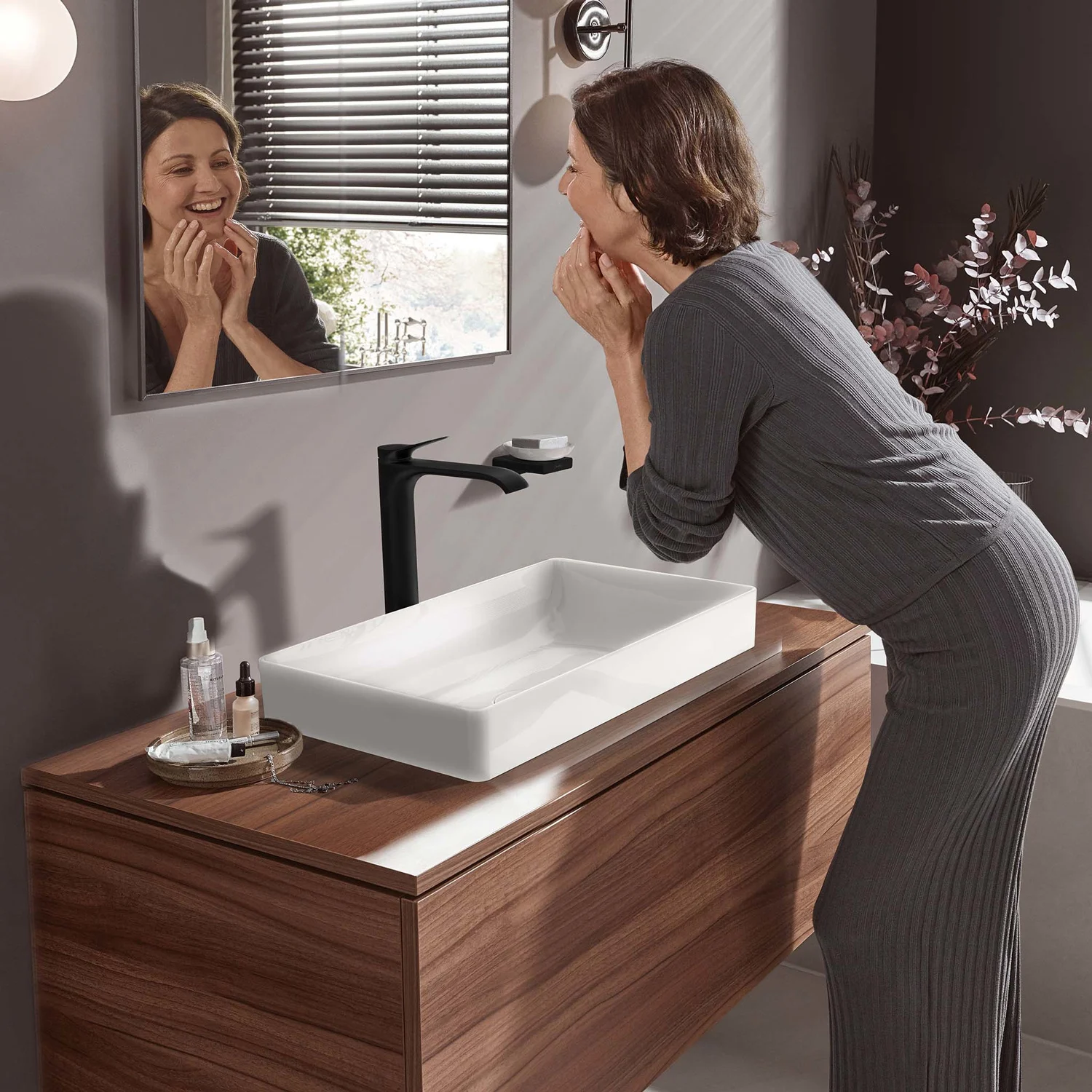 Kobieta przy umywalce z czarną baterią, hansgrohe