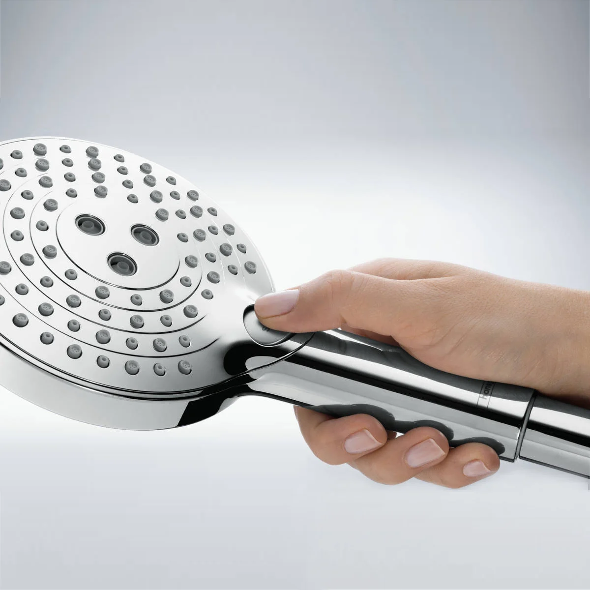 Ręka trzyma chromowaną słuchawkę prysznicową z boku, hansgrohe