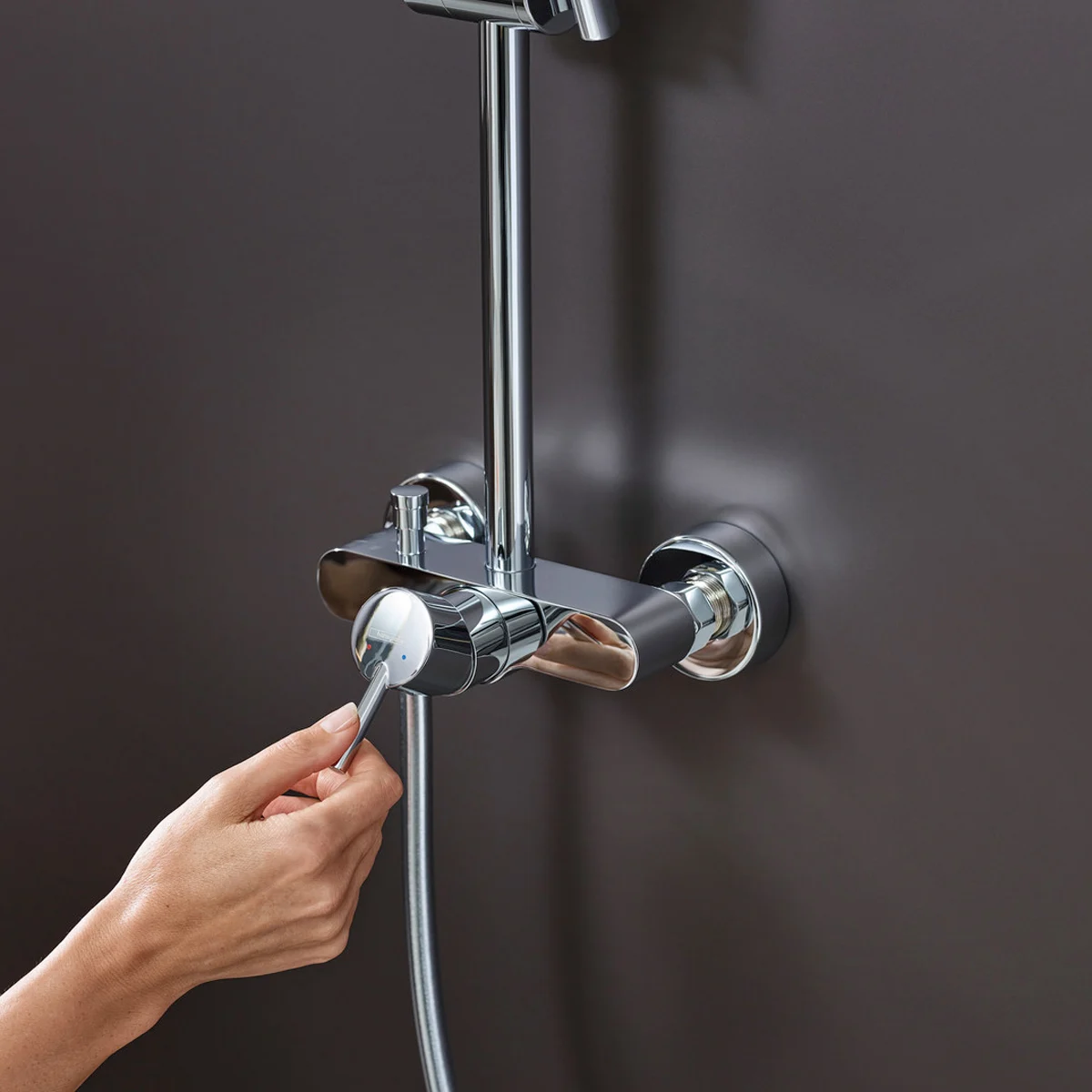 Ręka obsługująca armaturę prysznicową na ścianie, hansgrohe