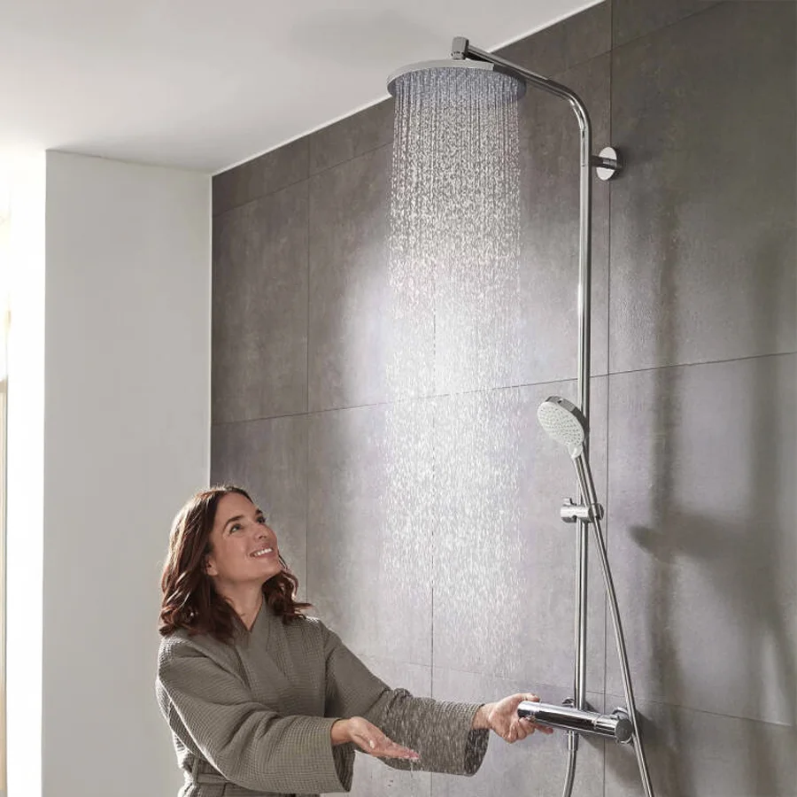 Kobieta pod działającym prysznicem deszczowym w łazience, hansgrohe