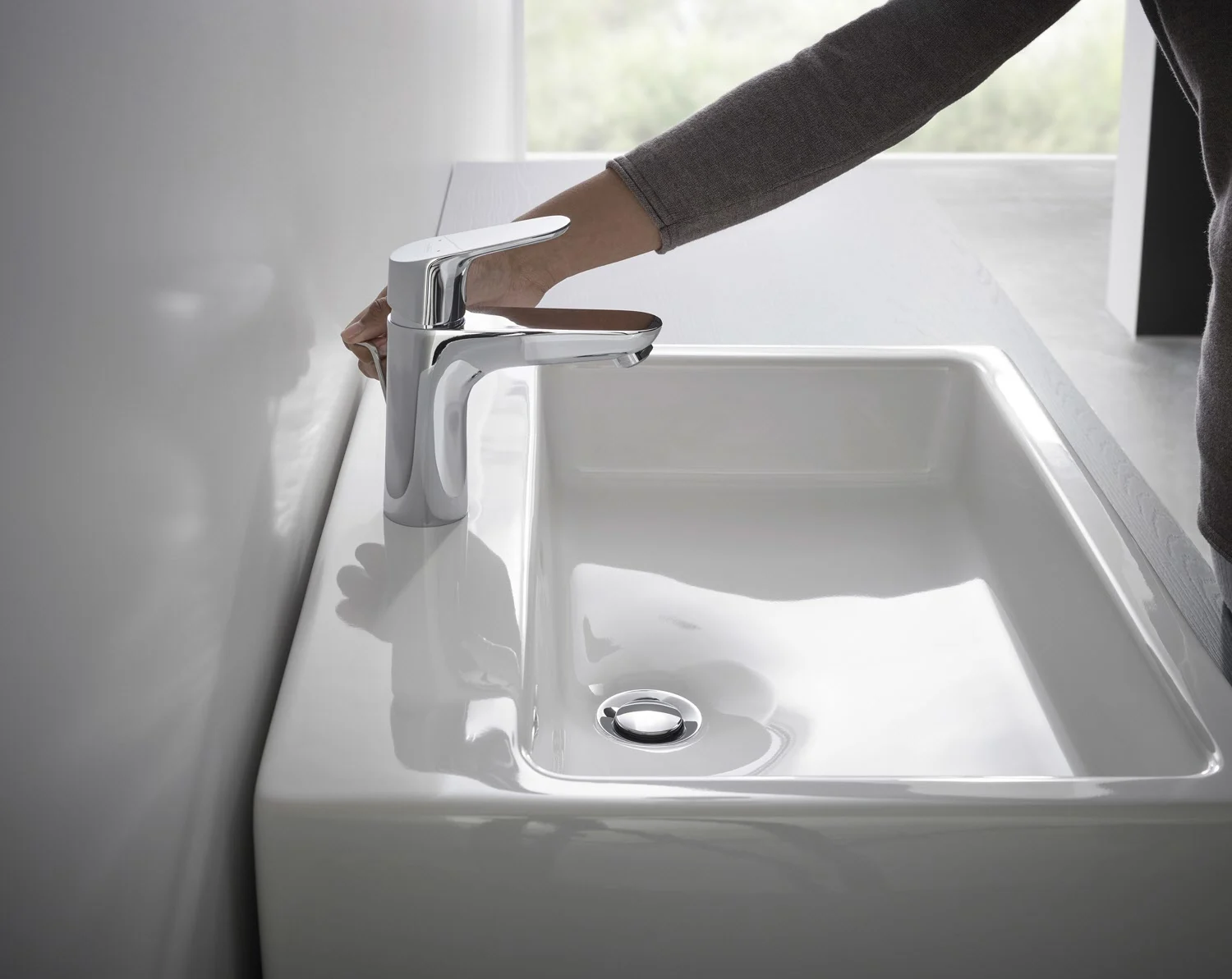 Mieszacz jednouchwytowy przy białej umywalce z ręką, hansgrohe