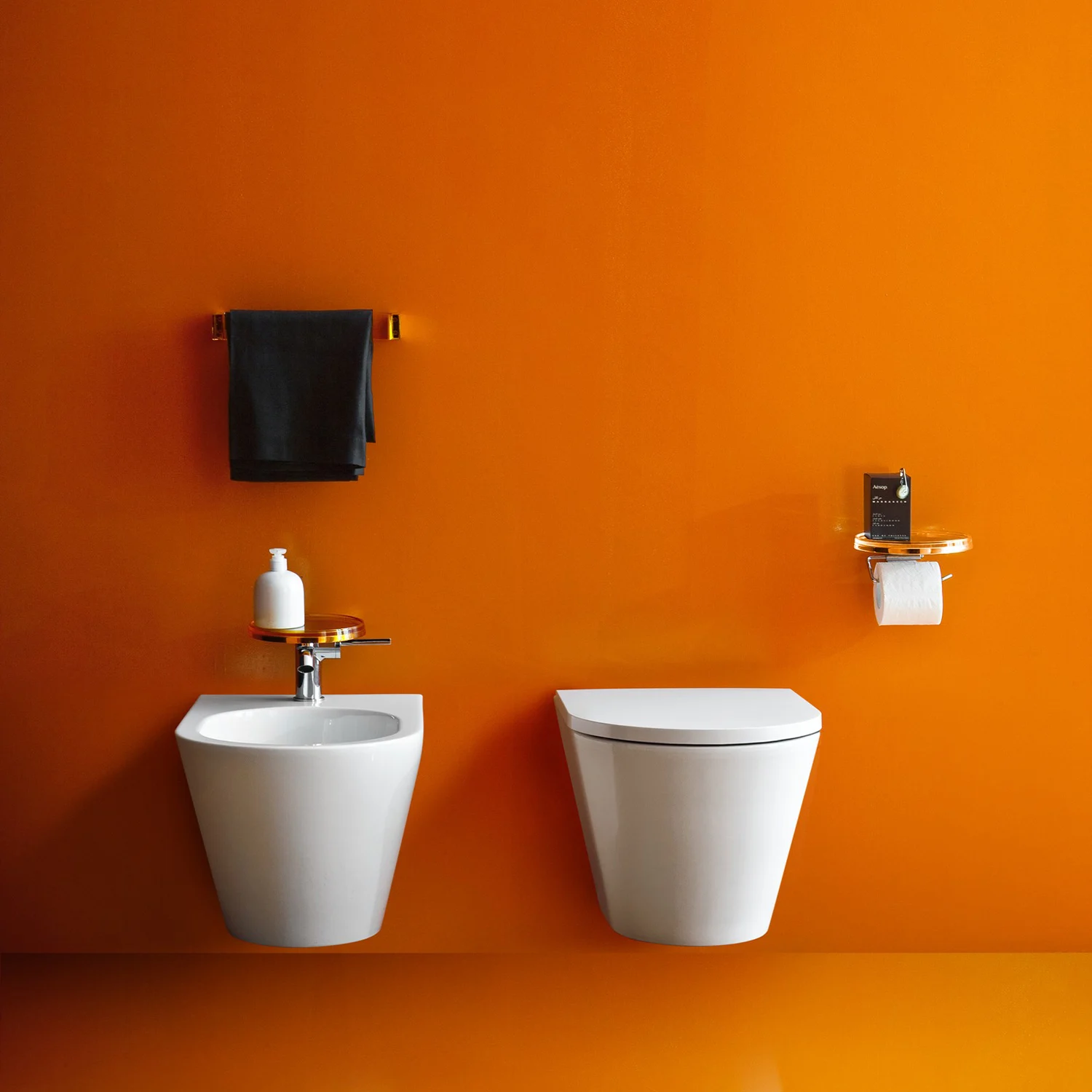 Biała toaleta i bidet na tle pomarańczowej ściany, Laufen