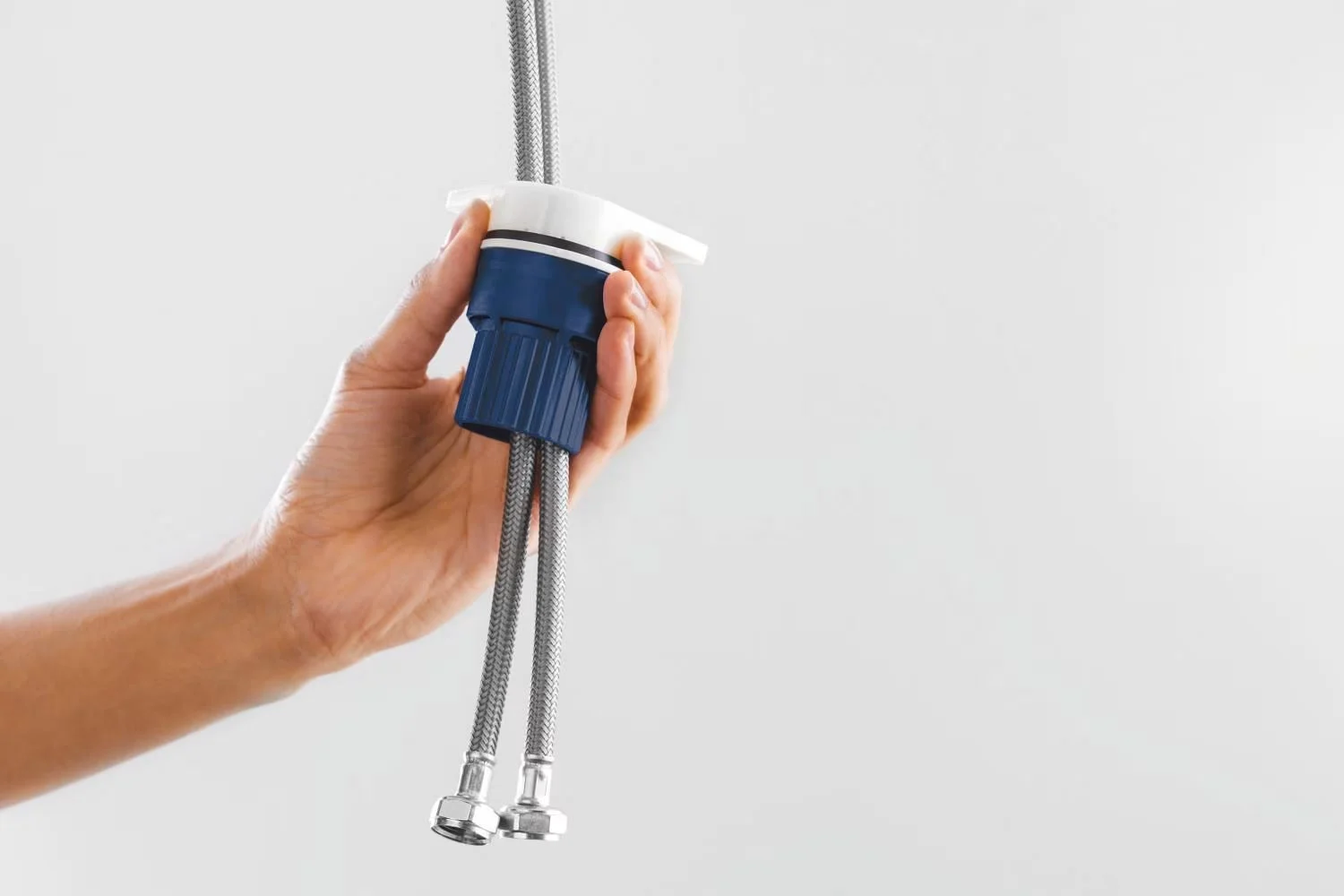 Ręka trzyma dwa elastyczne węże z łącznikiem, Grohe