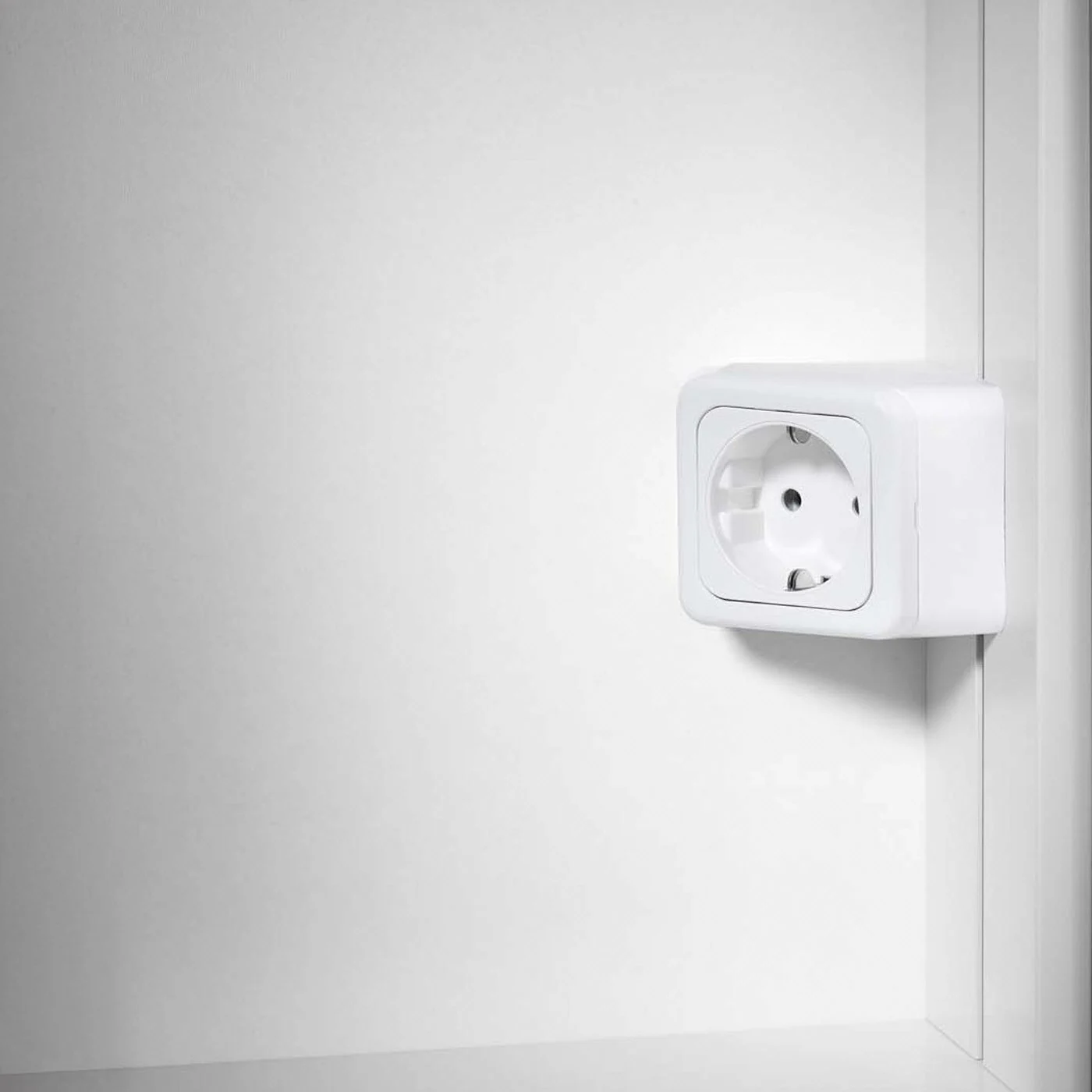 Białe gniazdko zamontowane w szafce, Schneider