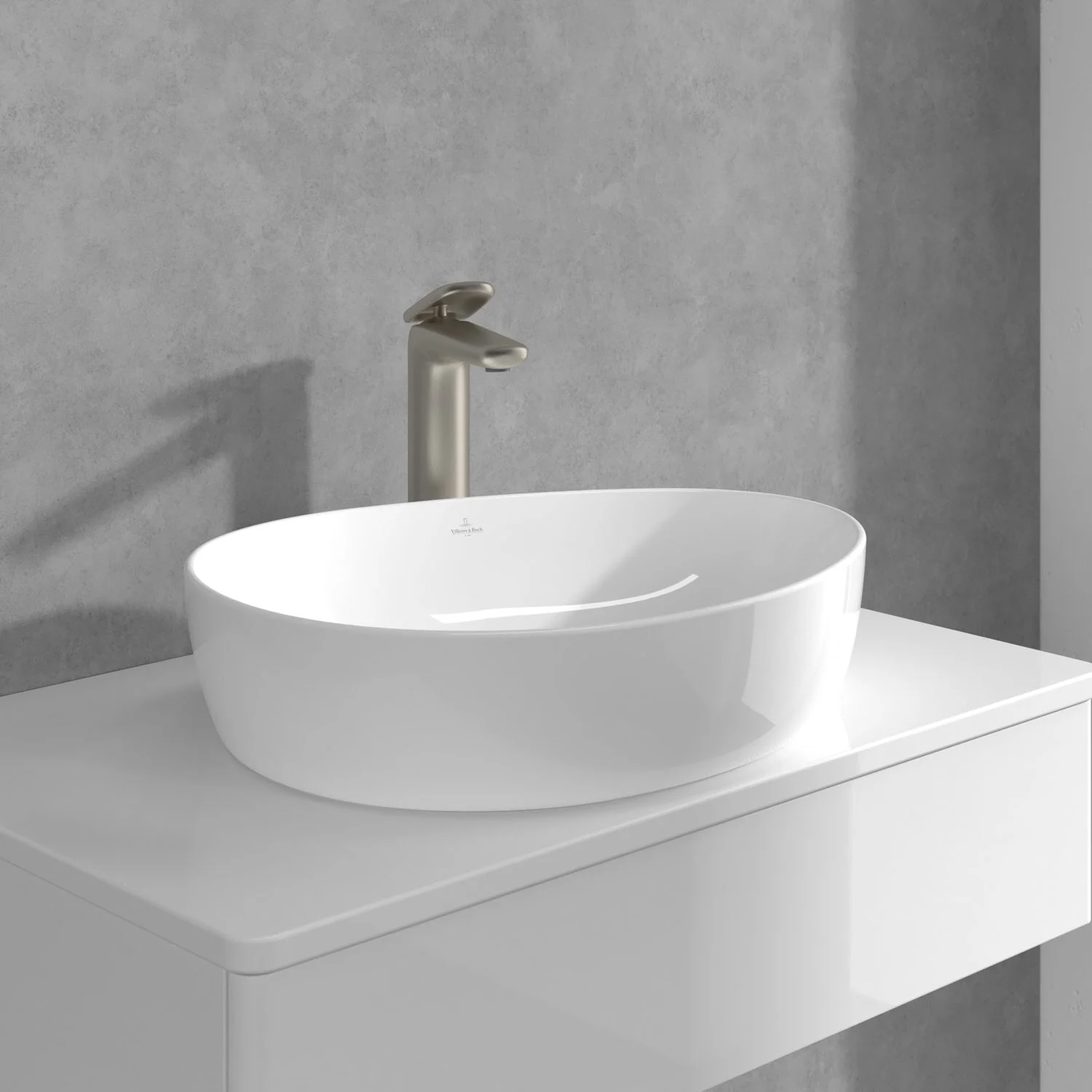 Złota bateria z białą umywalką na tle szarej ściany, Villeroy & Boch