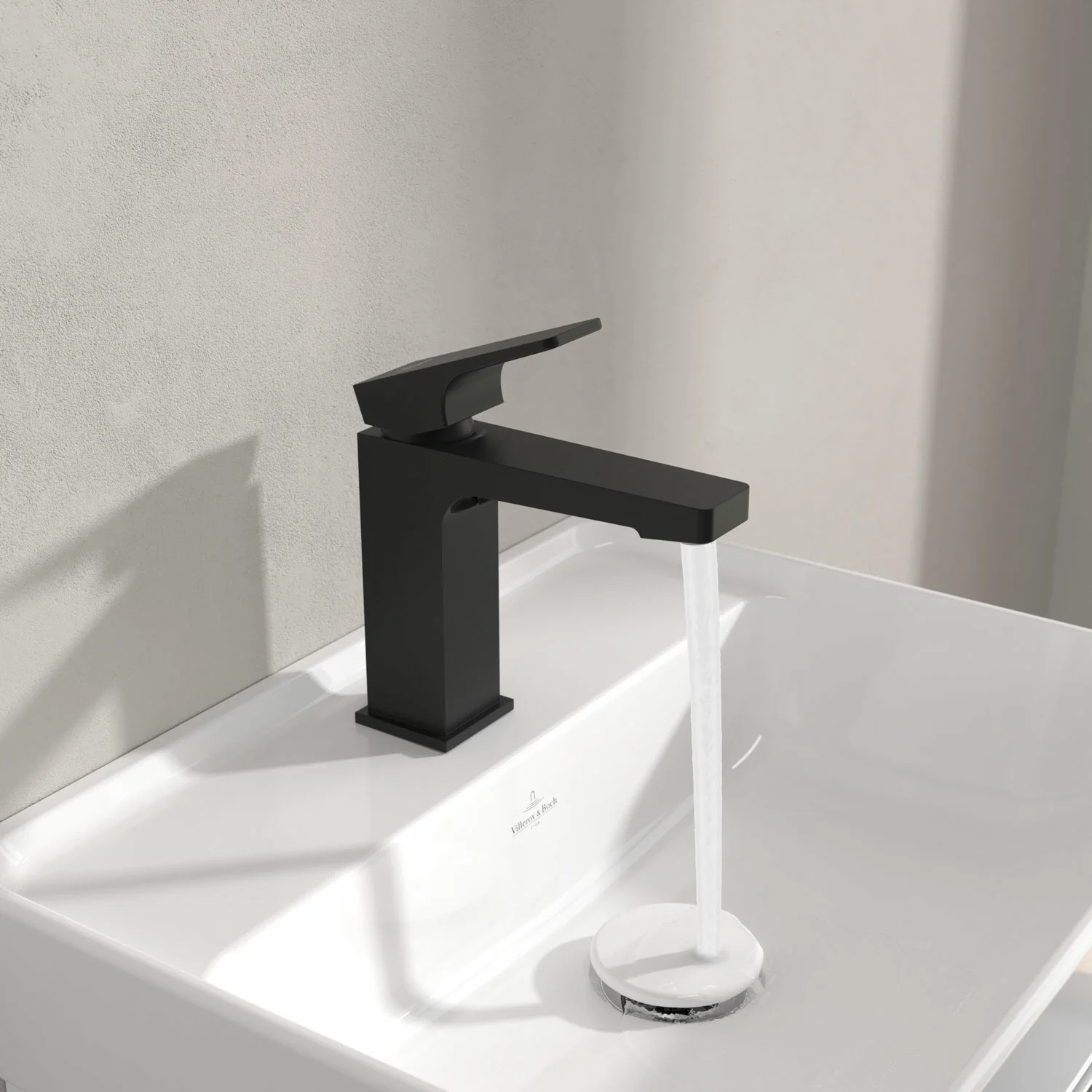 Czarna bateria na białej umywalce z bieżącą wodą, Villeroy & Boch