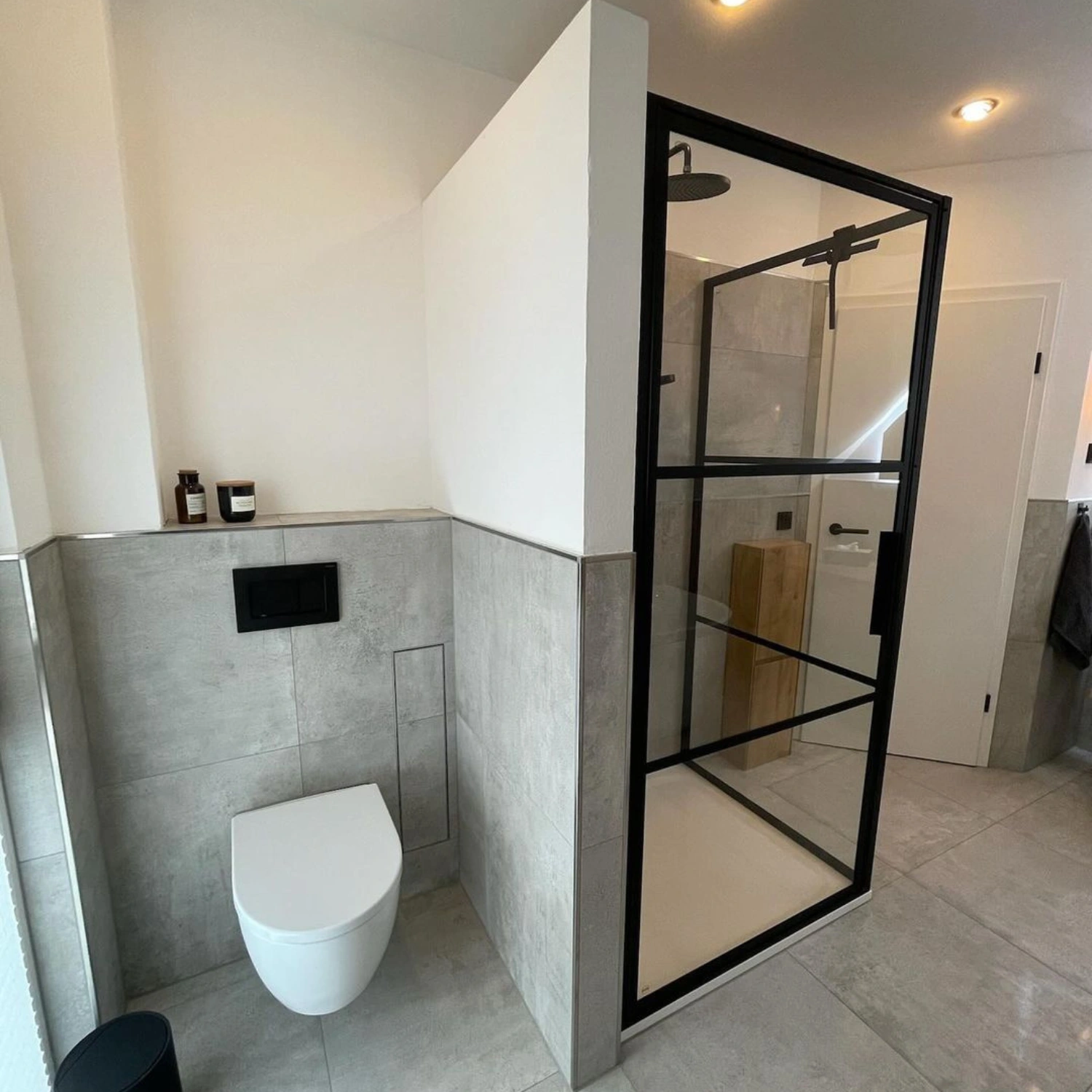 grau gefliestes Bad im minimalistischen, modernen Design mit schwarzer Dusche und weißem WC