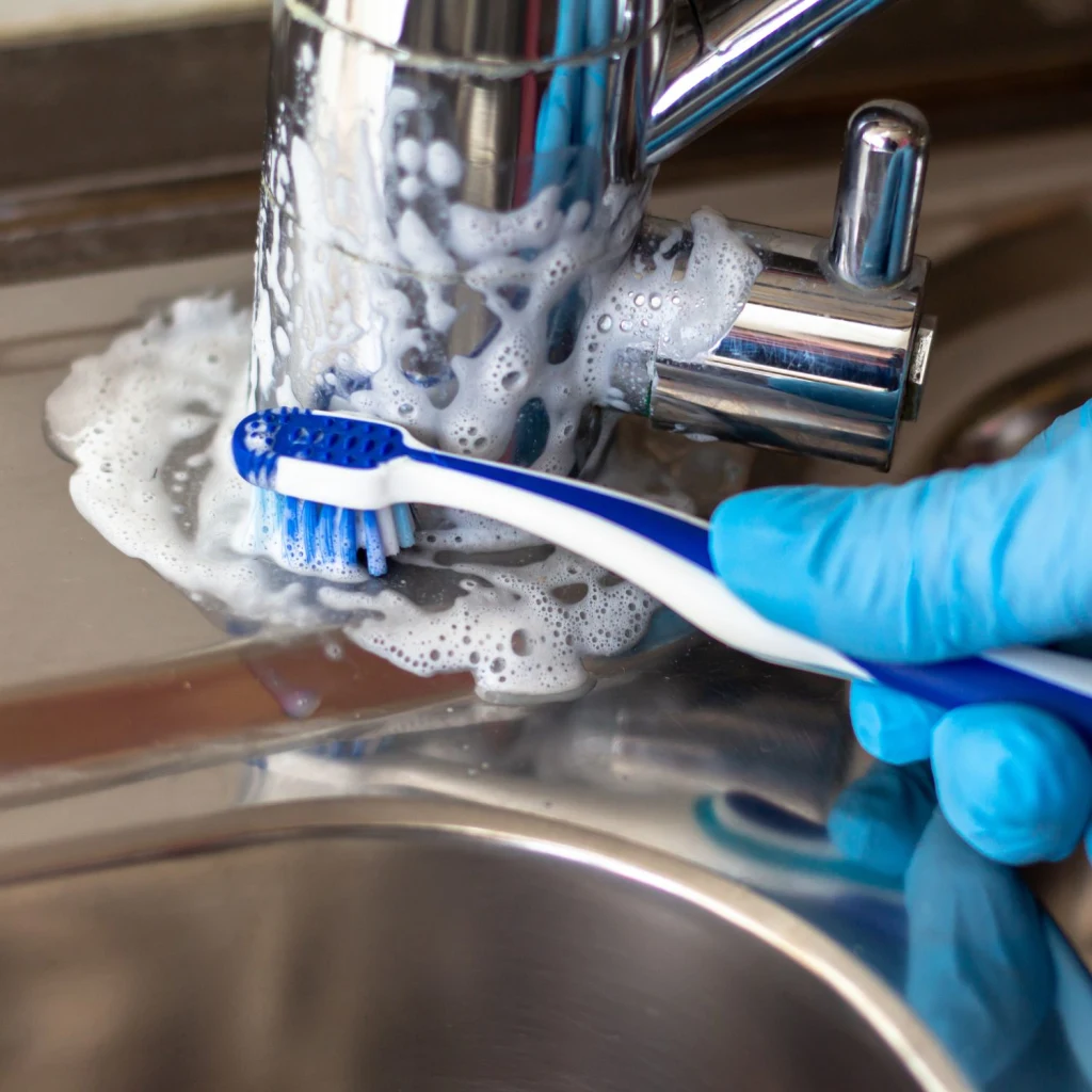 Grundliche Reinigung des Wasserhahns mit einer Zahnbürste.
