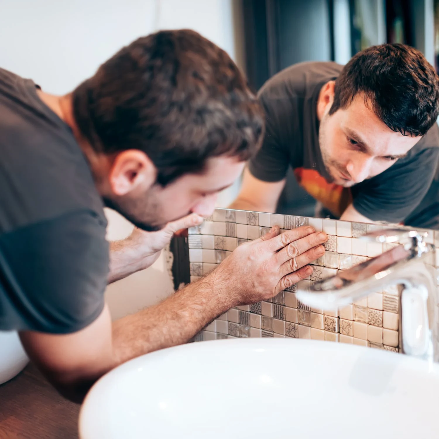 Ein Mann bringt eine Fliesentapete am Waschbecken an
